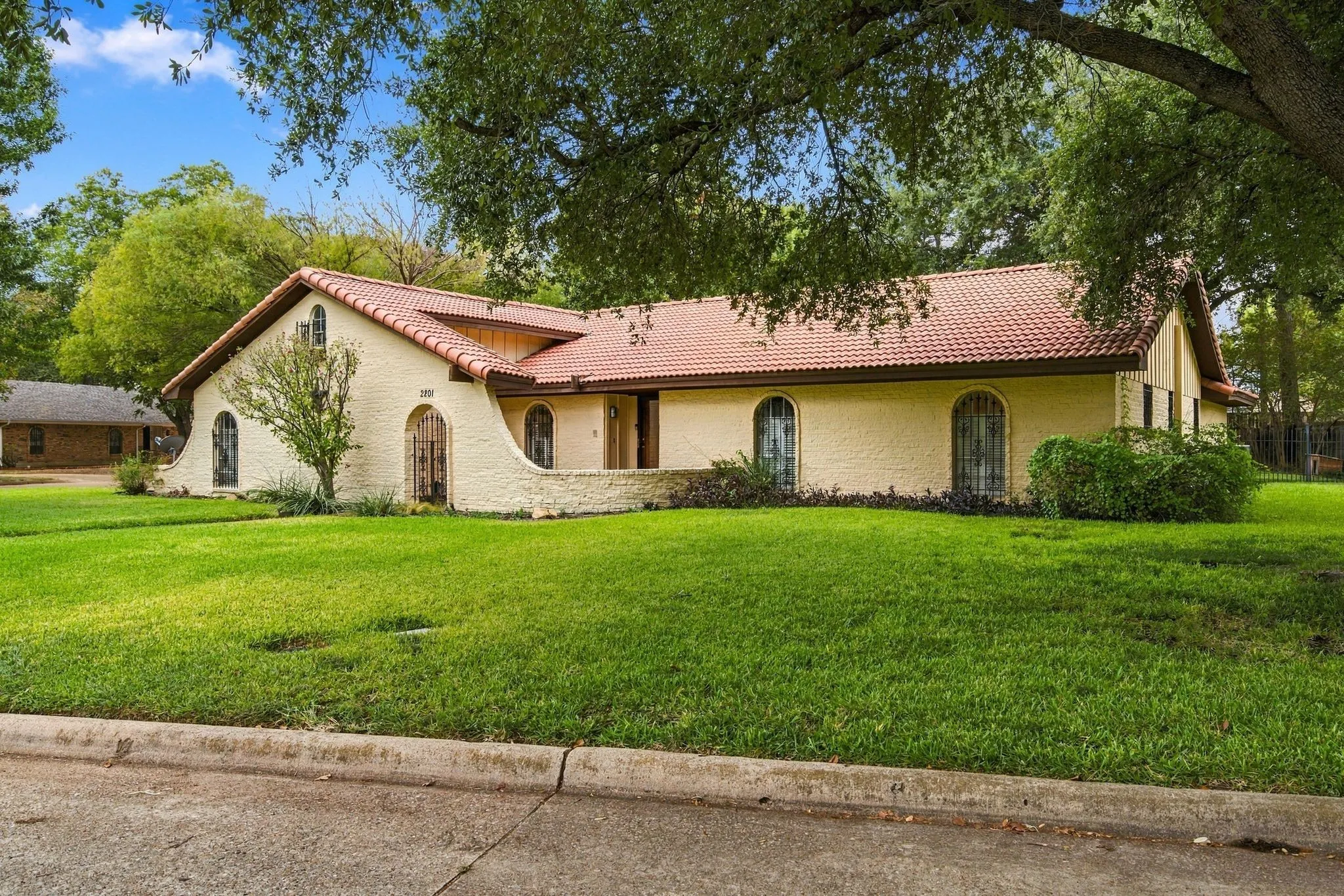 Brick exterior with a concrete tile roof arched windows, and a curved entryway wall