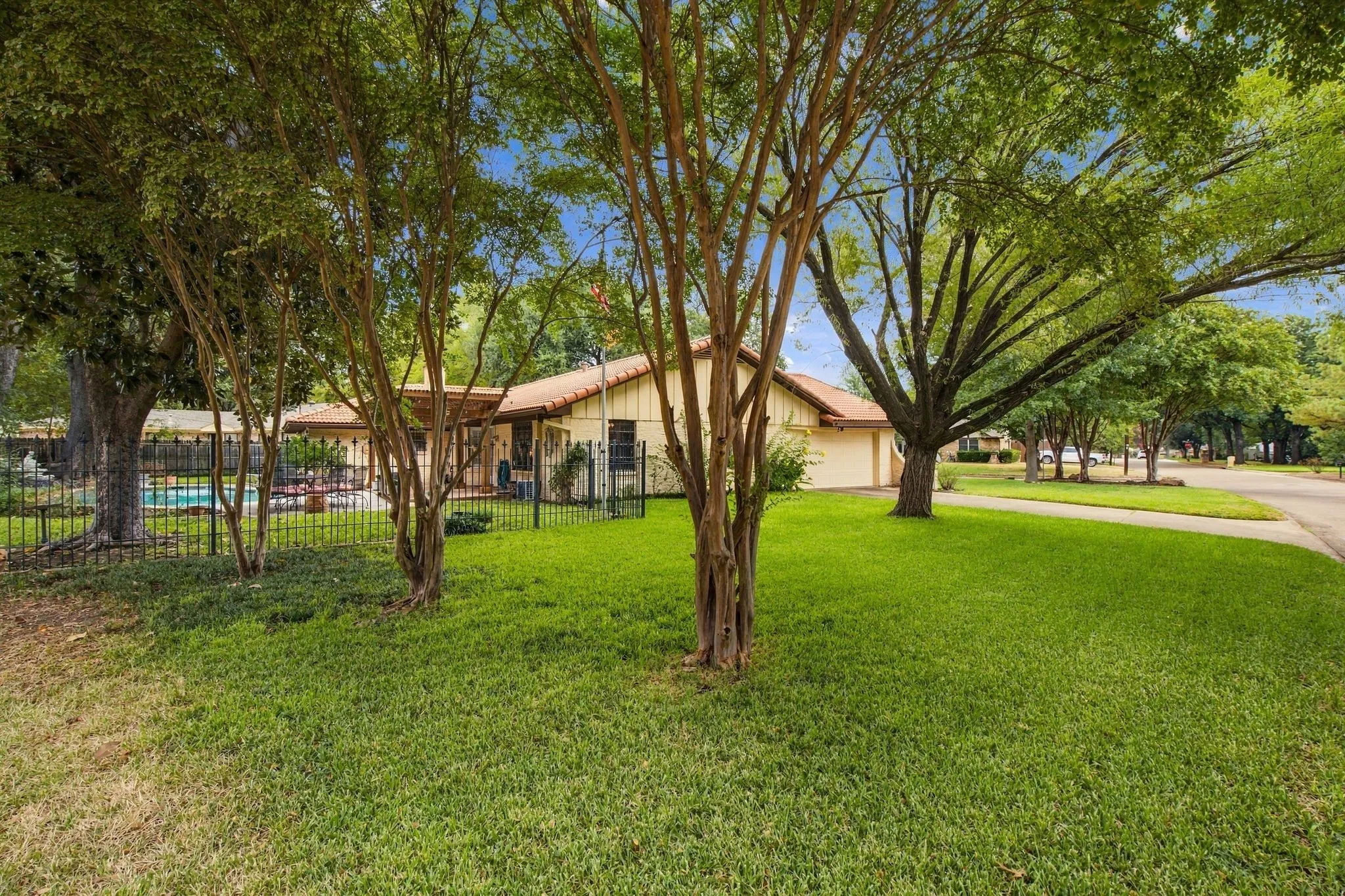 Expansive front yard with mature trees and a manicured lawn