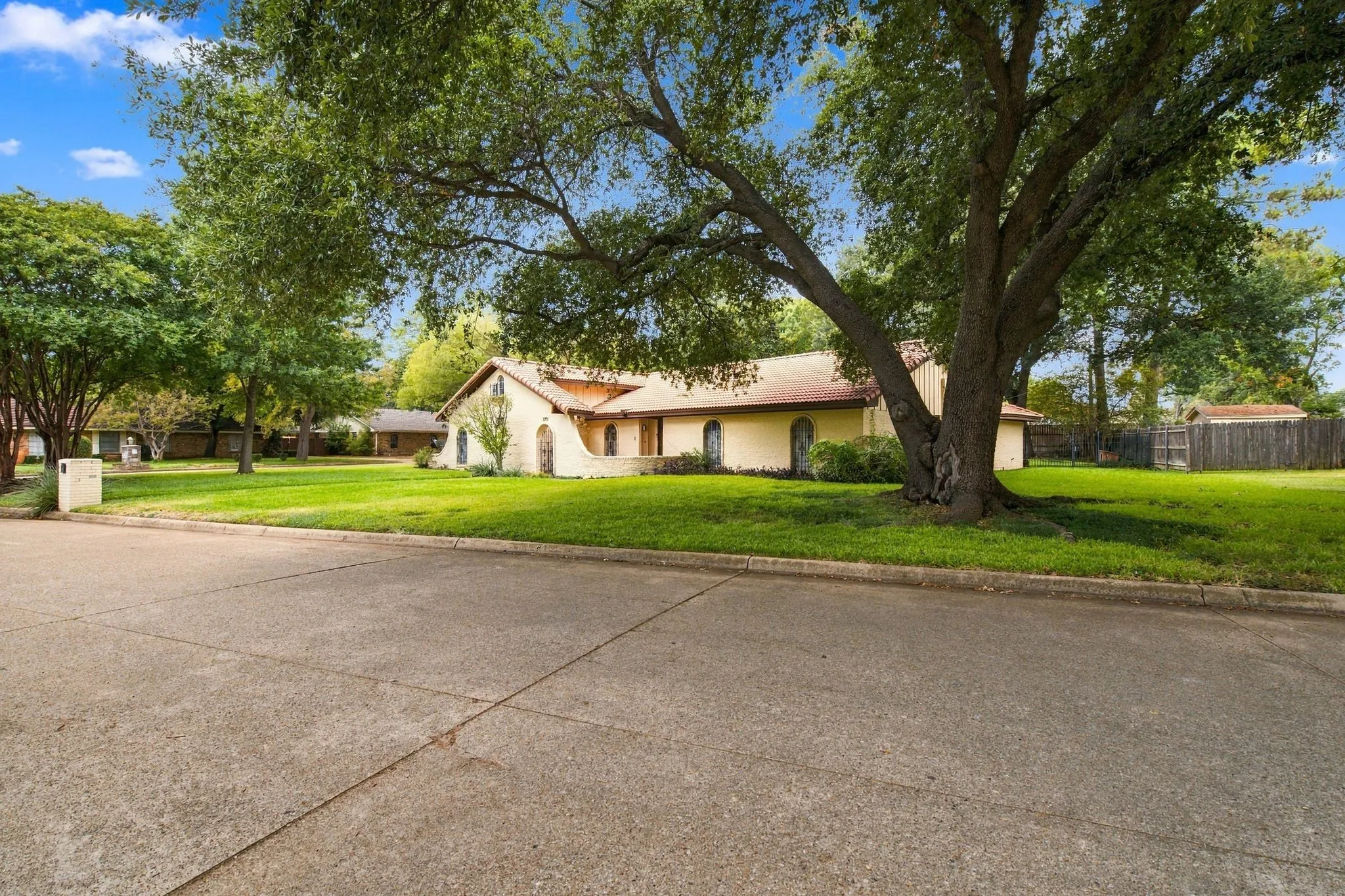 Cream Brick exterior with arch-top windows, complemented by a gabled roofline and surrounding mature trees