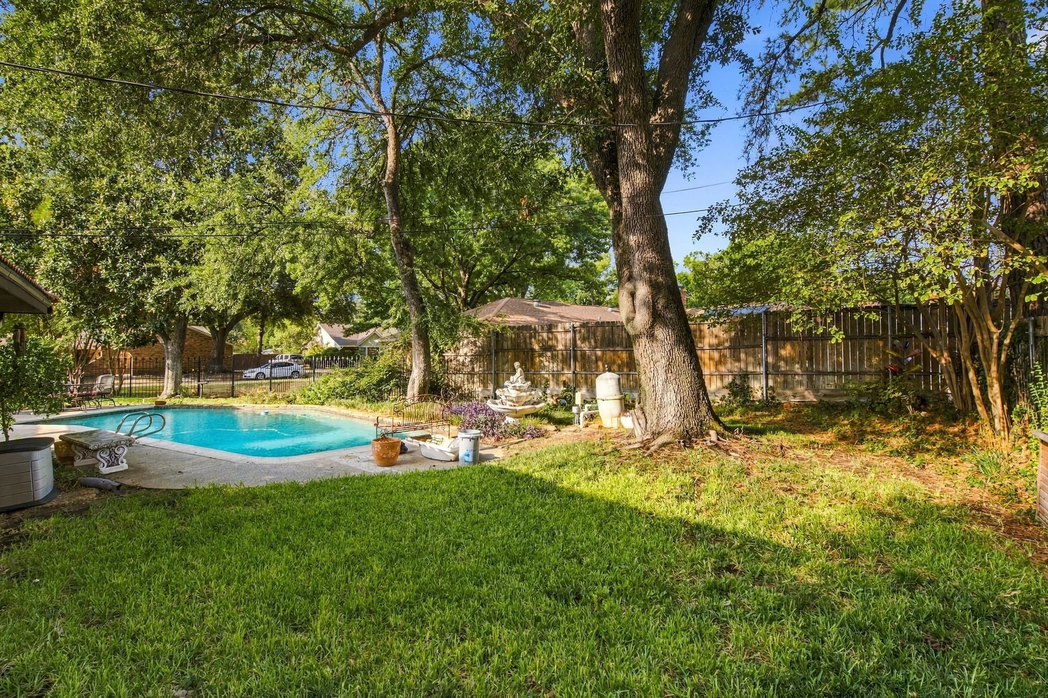 Expansive backyard featuring a lush lawn, mature trees, and a built-in swimming pool
