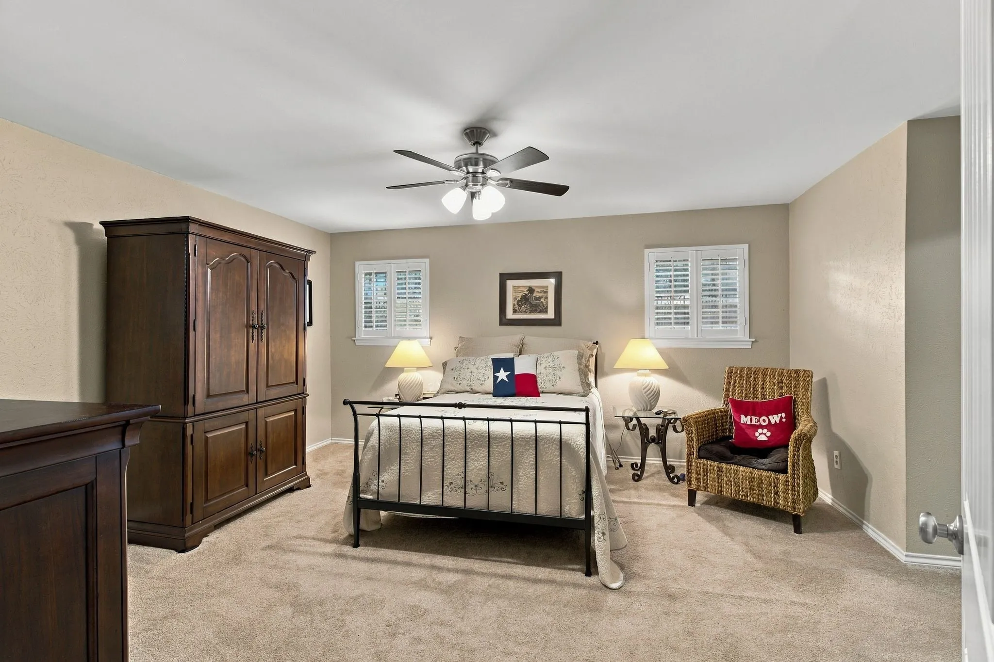 Carpeted bedroom with a ceiling fan, two windows, and neutral wall tones