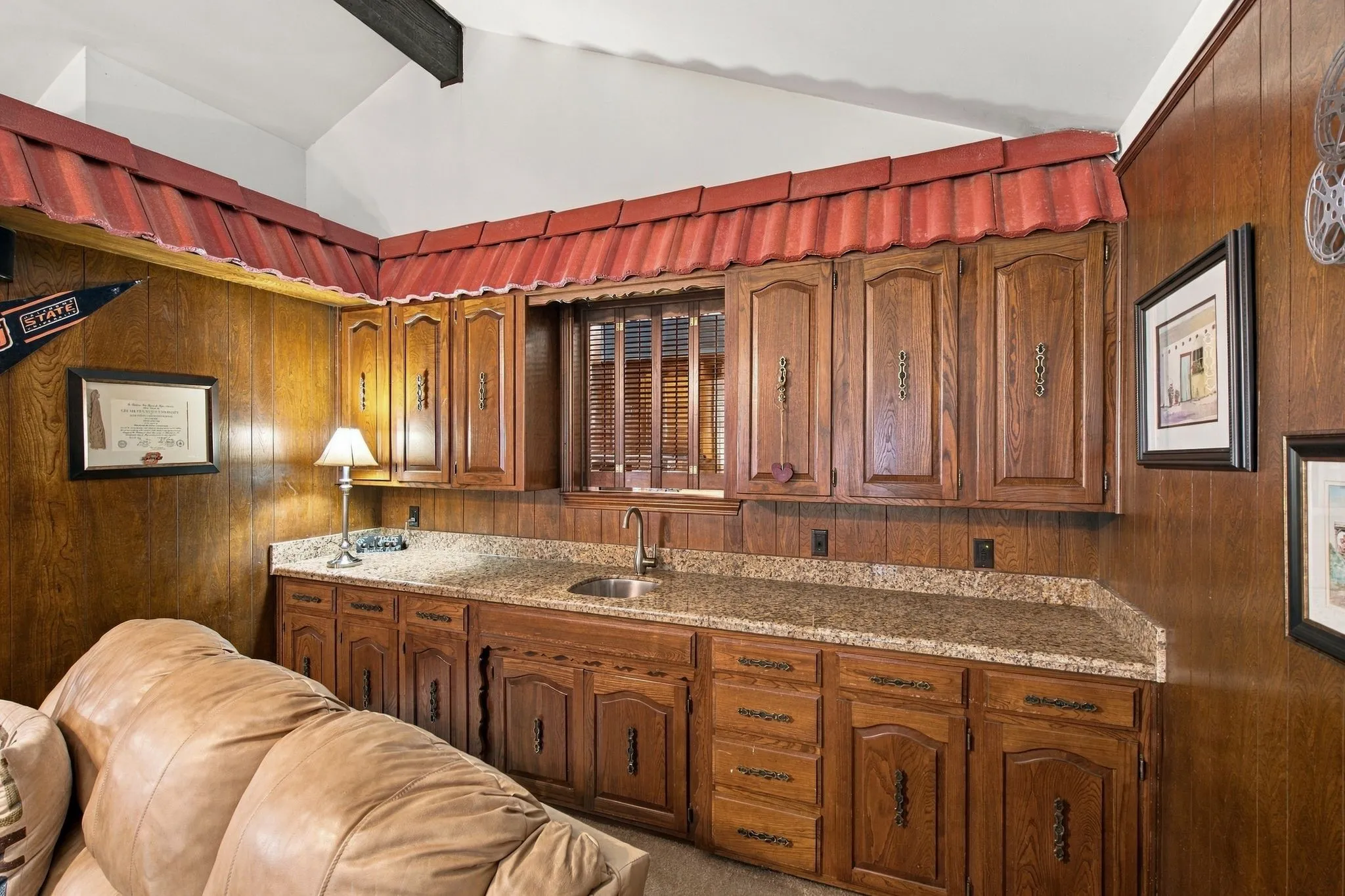 Wood-paneled walls featuring built-in cabinetry, a countertop with an integrated sink, and overhead storage