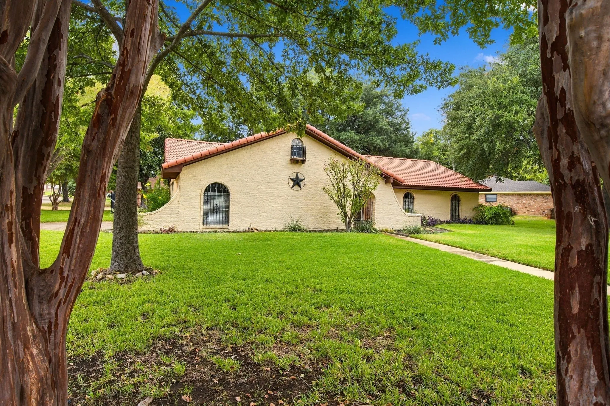Painted Brick exterior with a terra concrete tile roof, multiple arched windows, and a manicured lawn