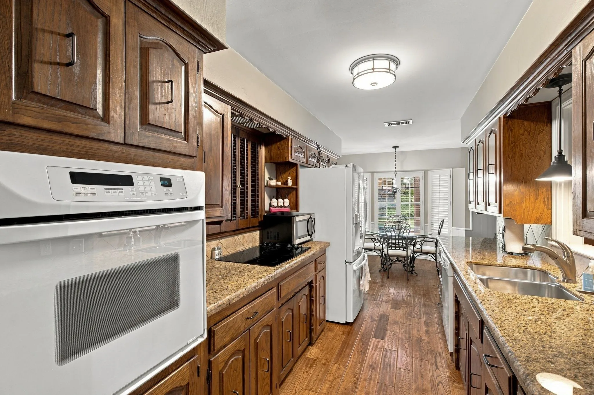 Wood-finish flooring, built-in oven, integrated stovetop, dual basin sink, and granite-style countertops