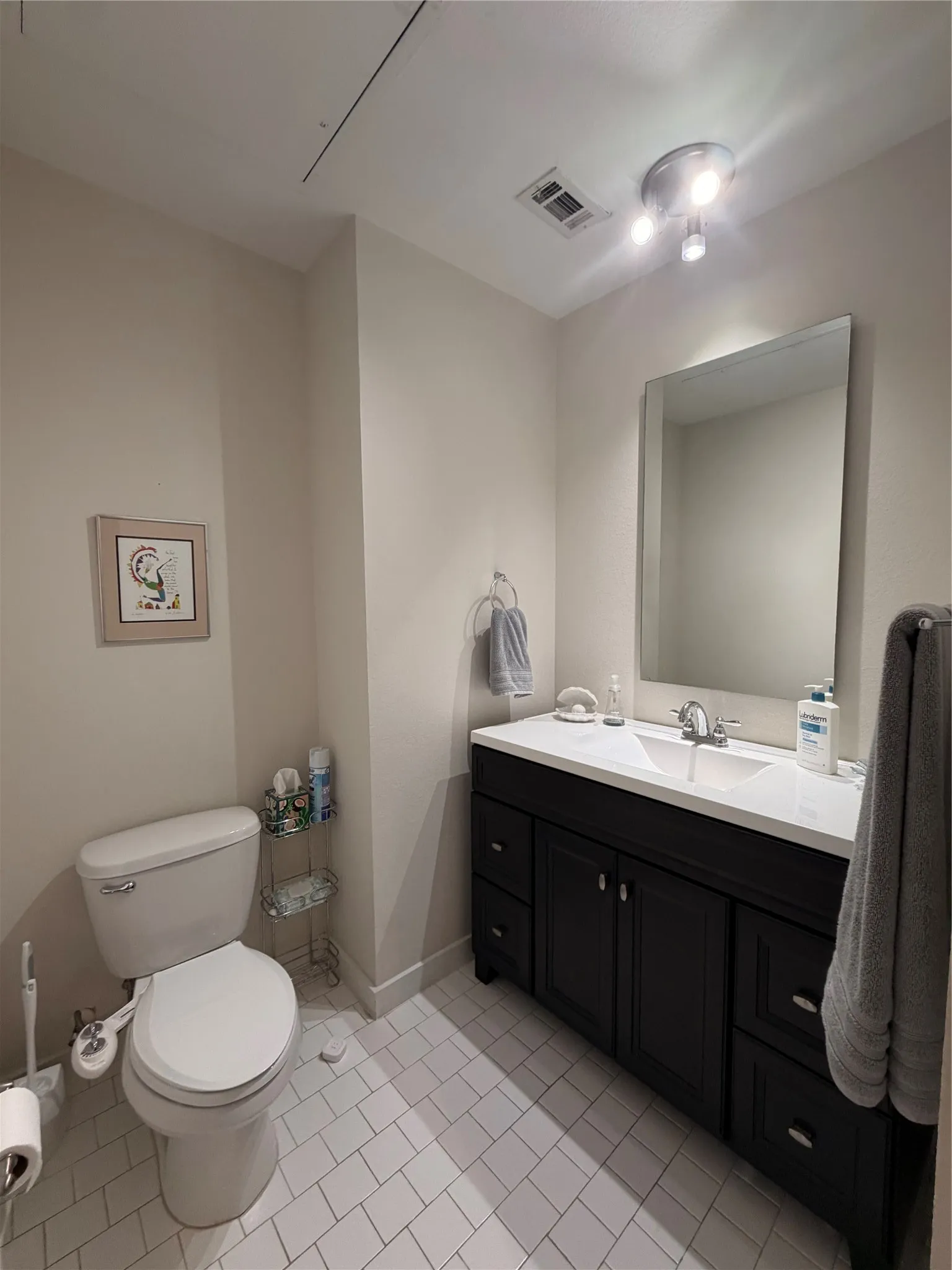 Vanity with dual sinks, white countertop, and dark wood cabinetry