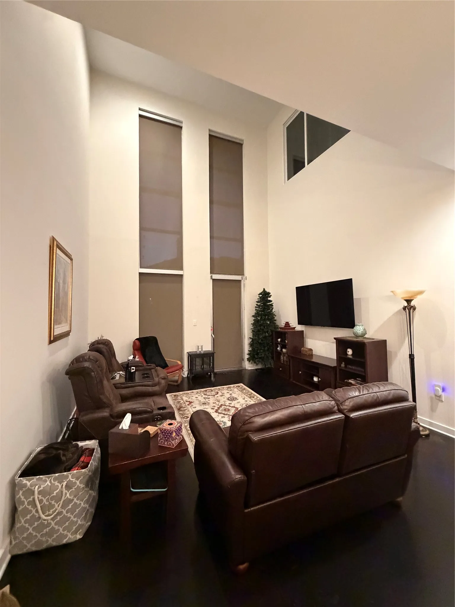 Vaulted ceilings with high windows, dark wood-finish flooring, and built-in wall lighting