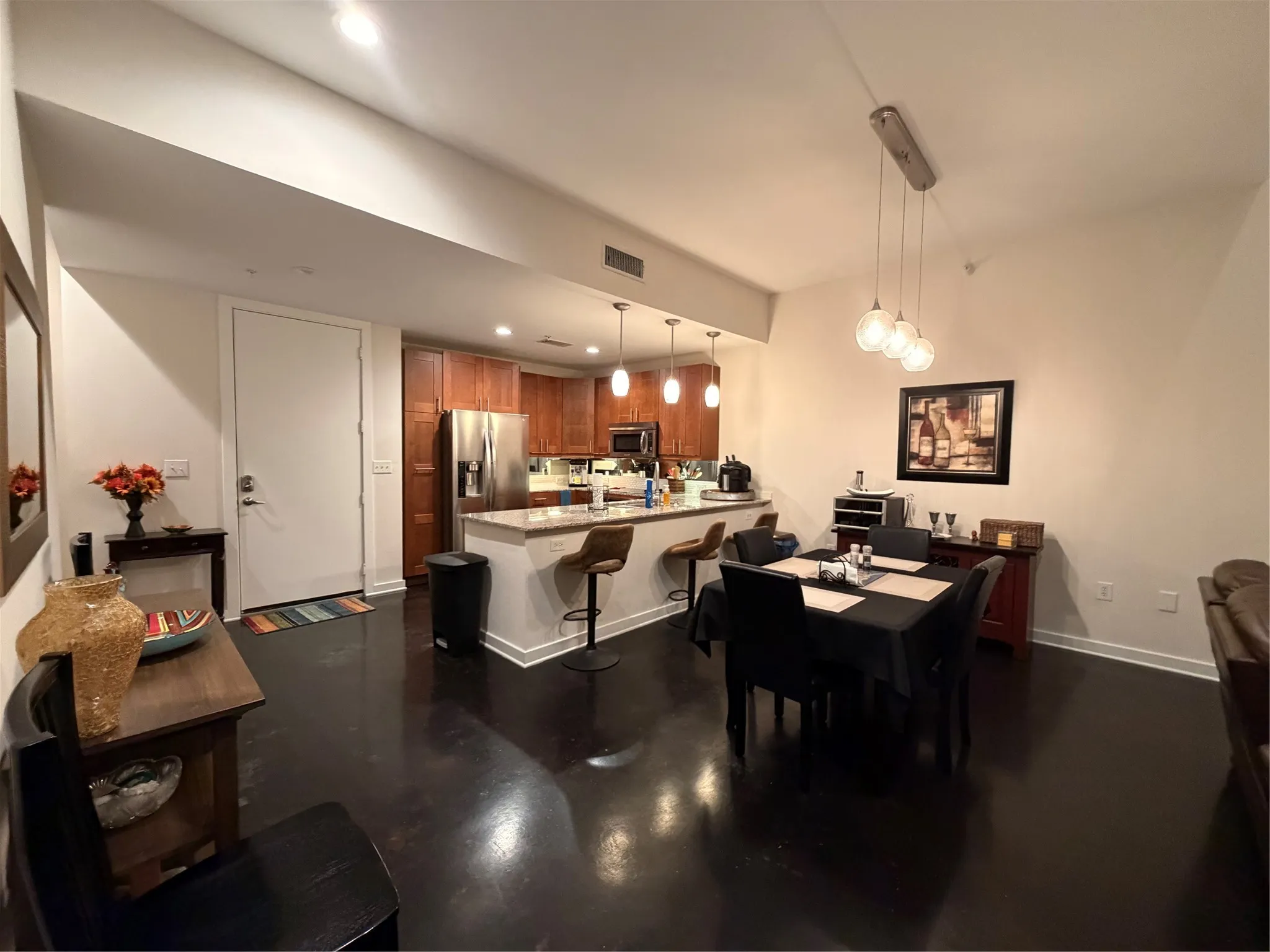 Kitchen featuring wood-finish cabinetry, stainless steel appliances, and a light-toned countertop with a breakfast bar