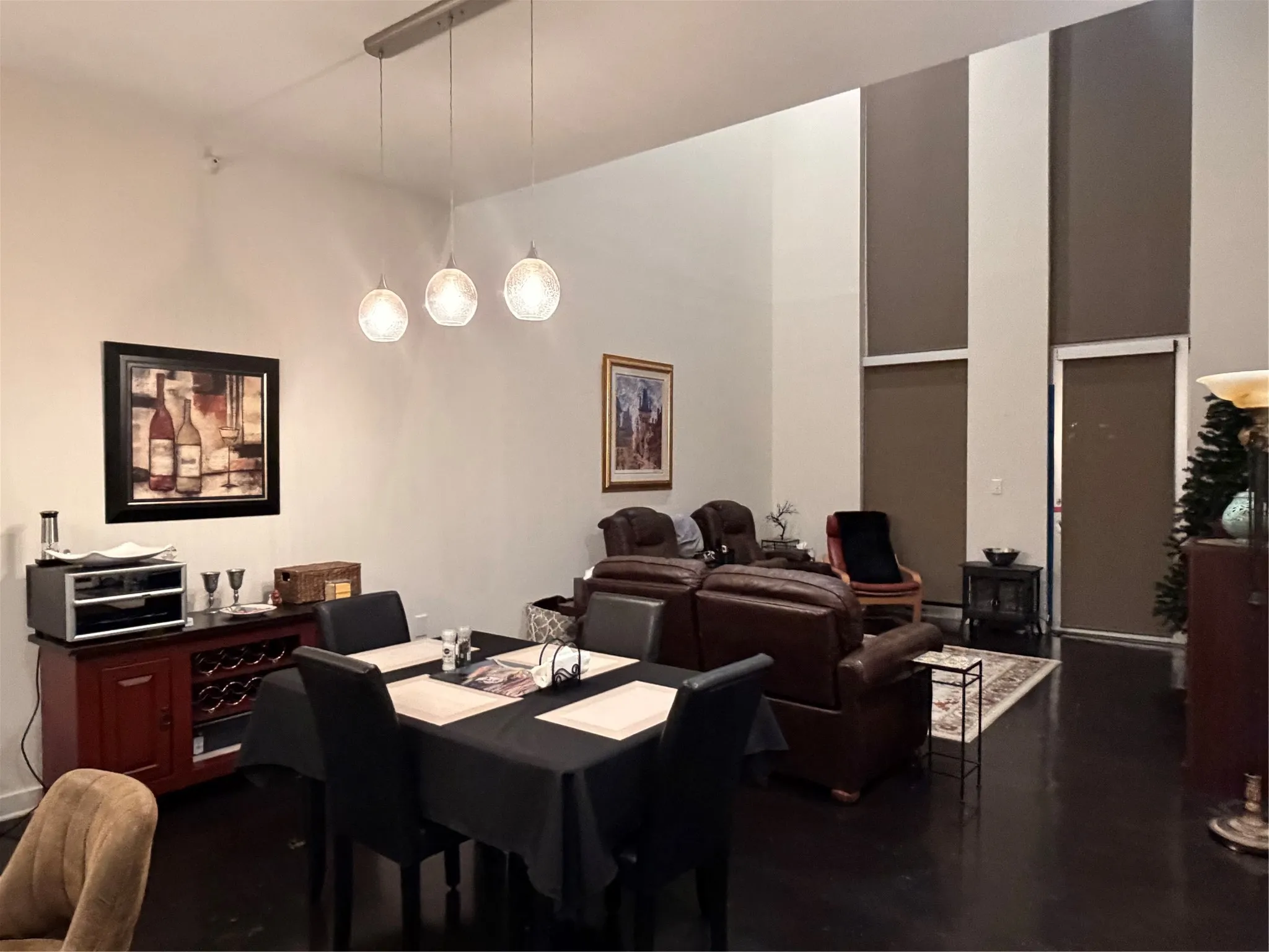 High ceilings with tall windows, dark wood-finish flooring, modern pendant lighting, and a built-in wine rack