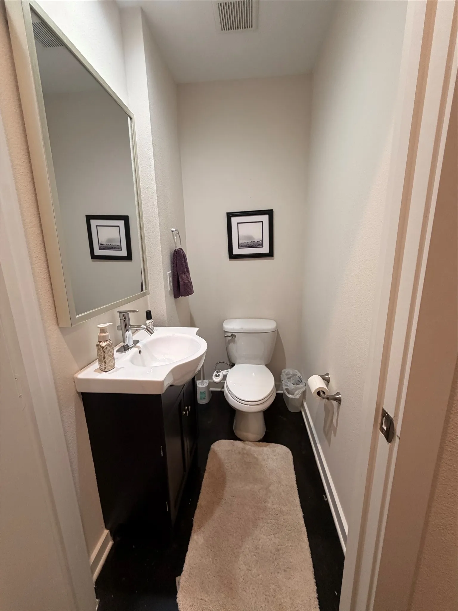 Dark wood-finish vanity with an integrated white sink and stainless steel faucet