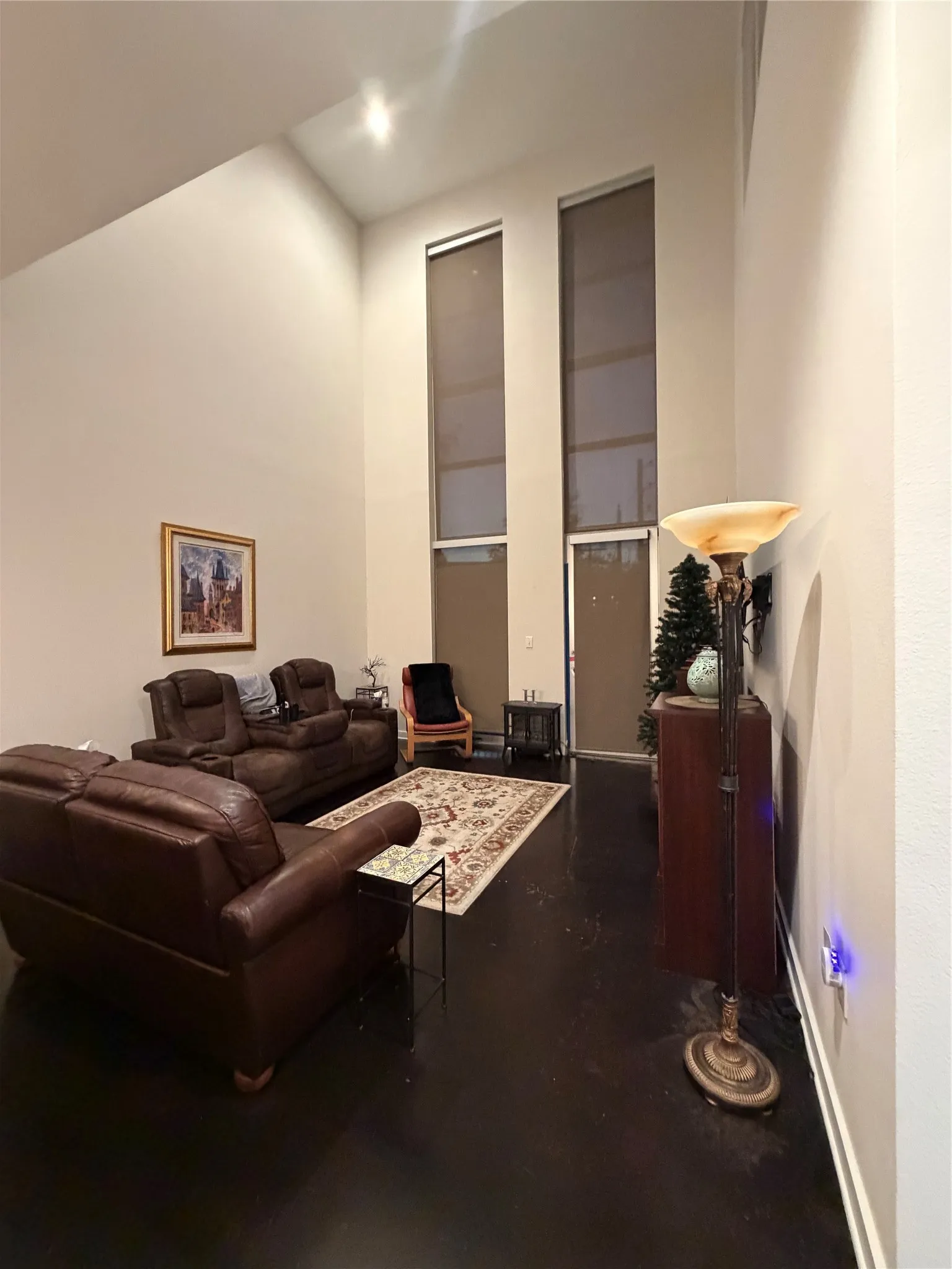 Vaulted ceilings, large vertical windows with roller shades, recessed lighting, and dark-toned flooring