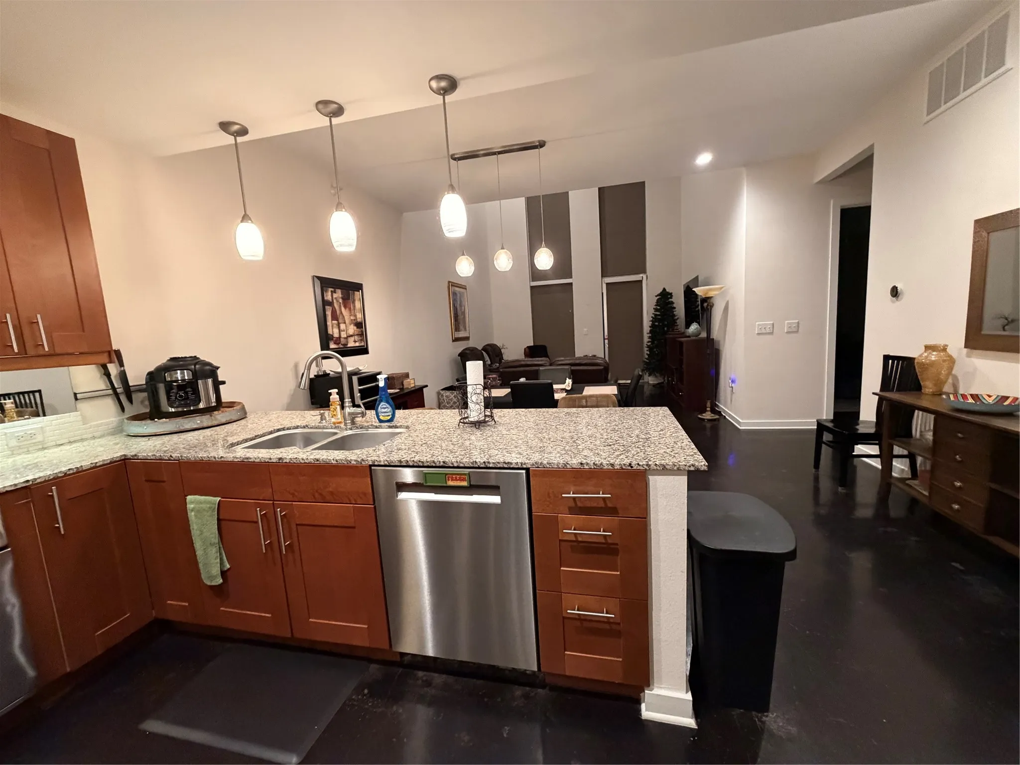 Kitchen featuring wood cabinetry, granite-finish countertops, stainless steel dishwasher, and a double basin sink with a gooseneck faucet