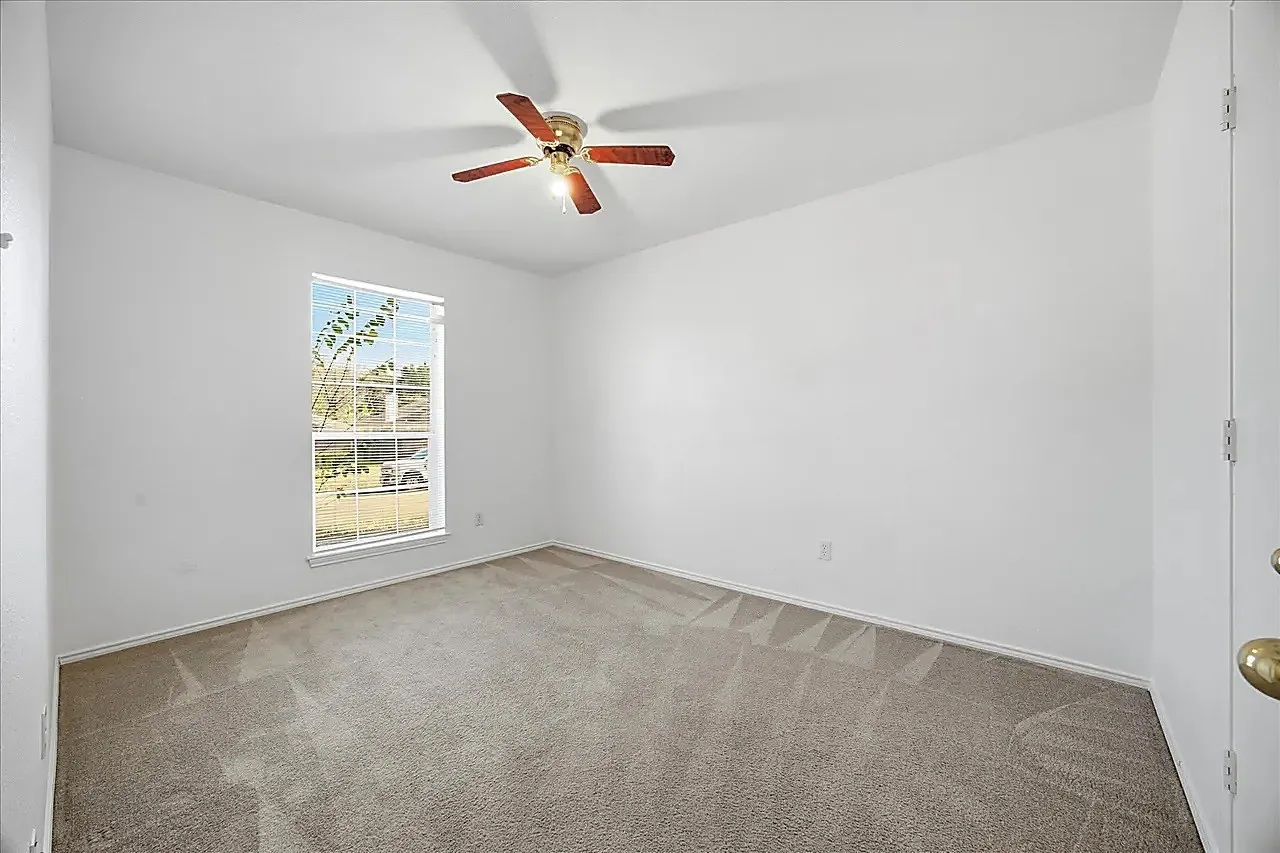 Neutral wall paint, ceiling fan with wood-finish blades, and window with blinds