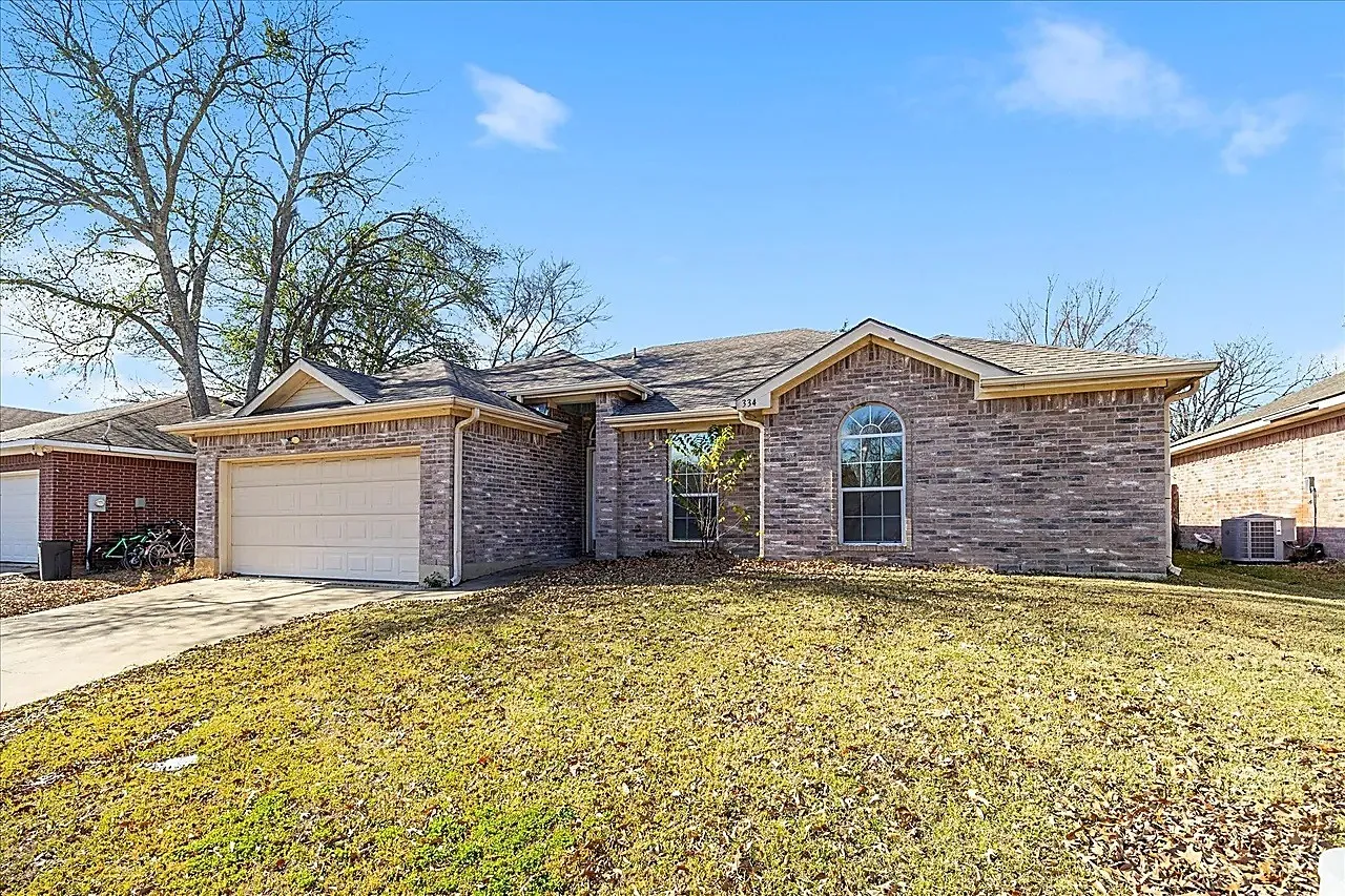 Brick exterior with an arched window, attached garage, and pitched roof