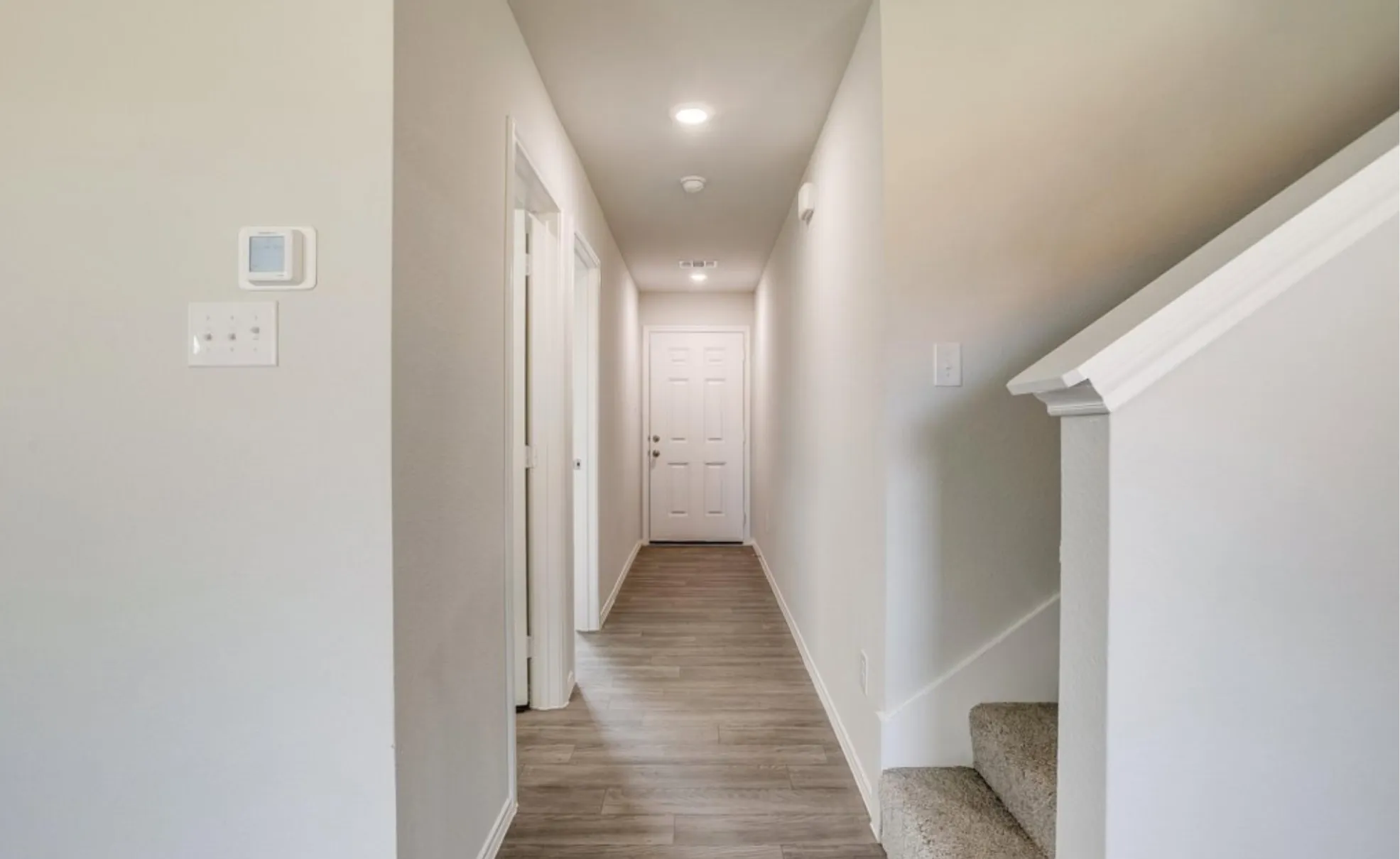 Hallway featuring wood-finish flooring, recessed lighting, and a white interior door