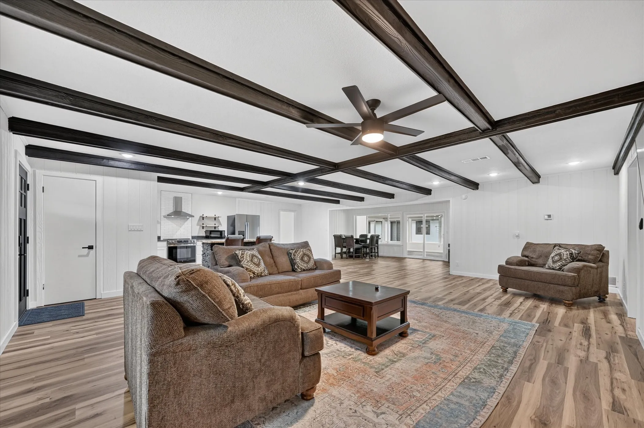 Exposed ceiling beams, wood-finish flooring, recessed lighting, and a ceiling fan with integrated lighting