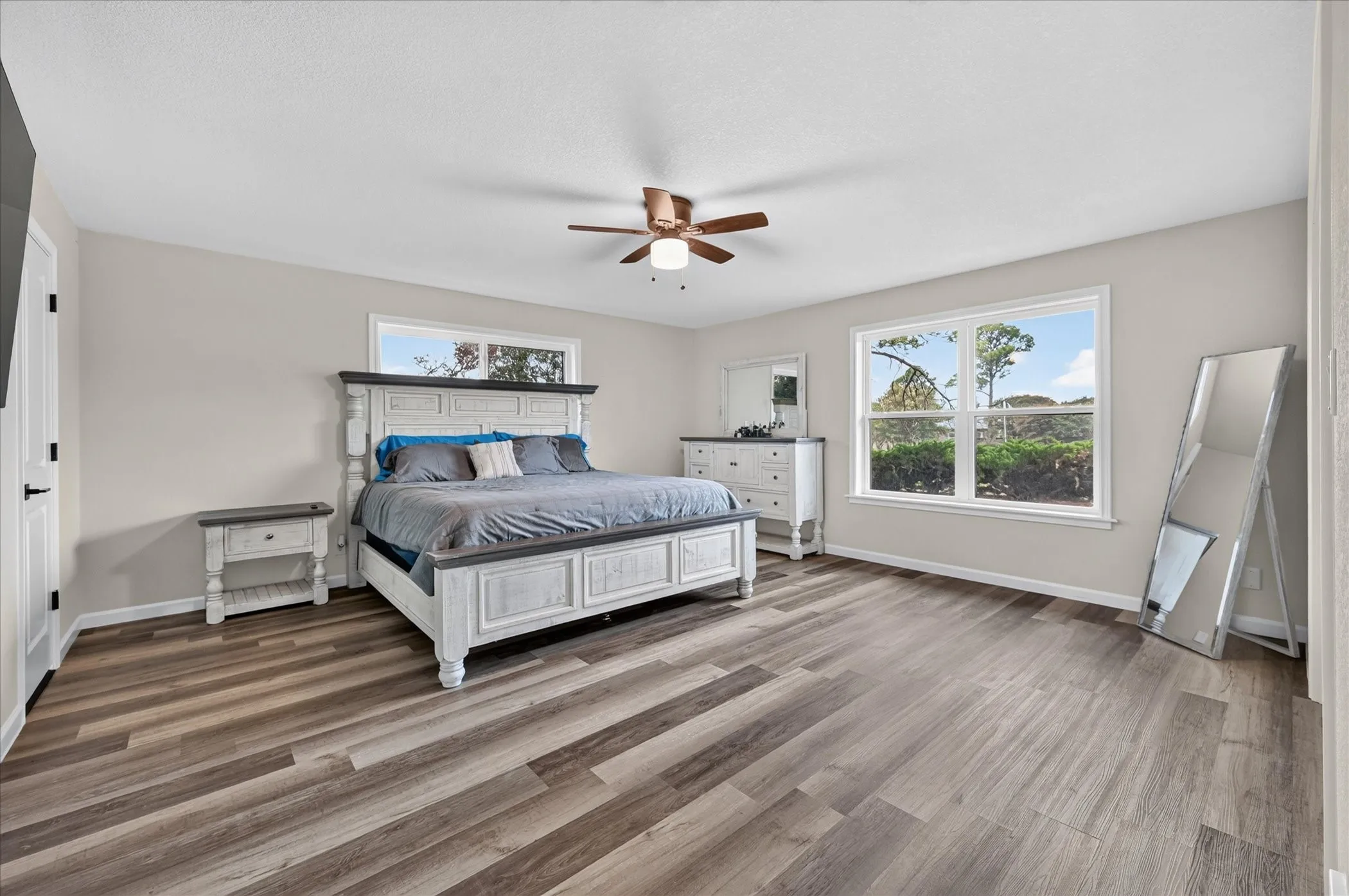 Wood-finish flooring throughout, multiple windows, and a ceiling fan with integrated lighting
