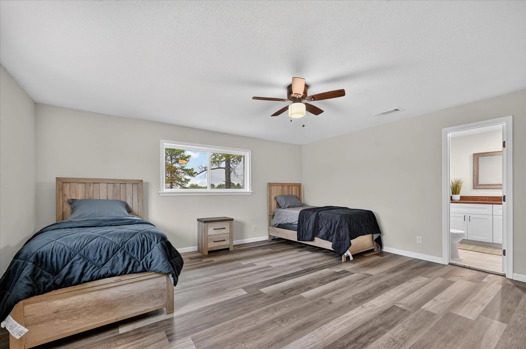 Spacious room featuring wood-finish flooring, a ceiling fan with integrated lighting, and a window providing natural light