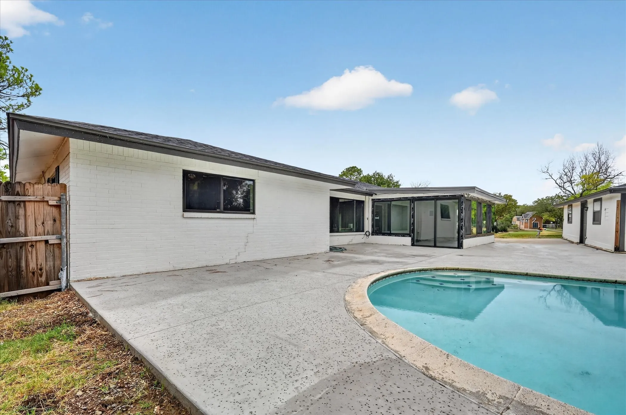Paved concrete patio surrounding an inground swimming pool with steps