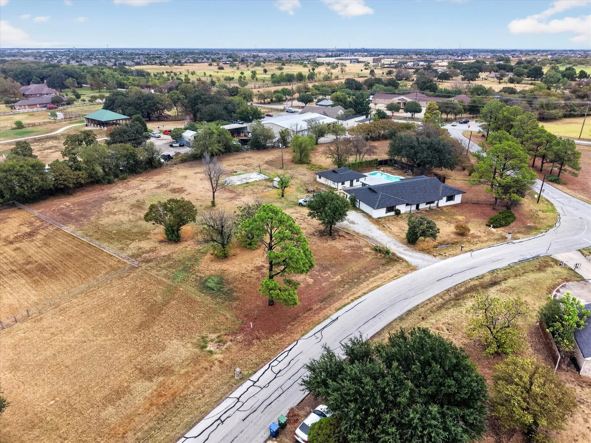 Aerial property perspective featuring a single-story residence, private pool, and expansive undeveloped land