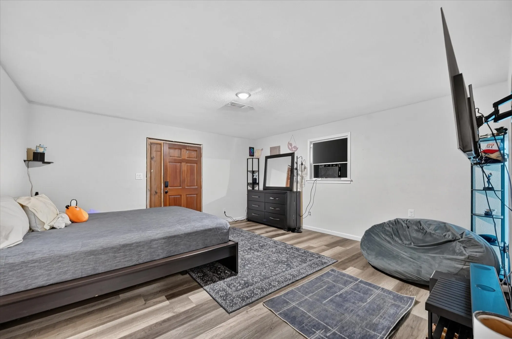 Wood-finish flooring, white walls, recessed ceiling light, and a prominent wood-panel door