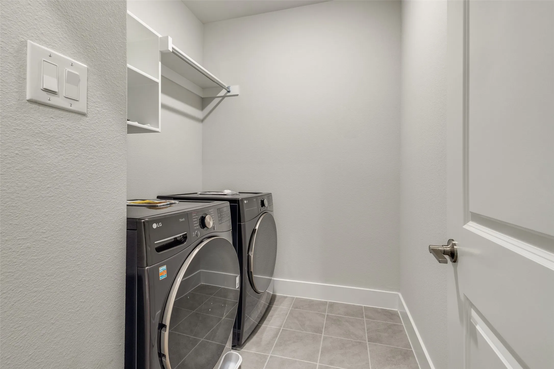 Laundry room with washer and clothes dryer and light tile patterned floors