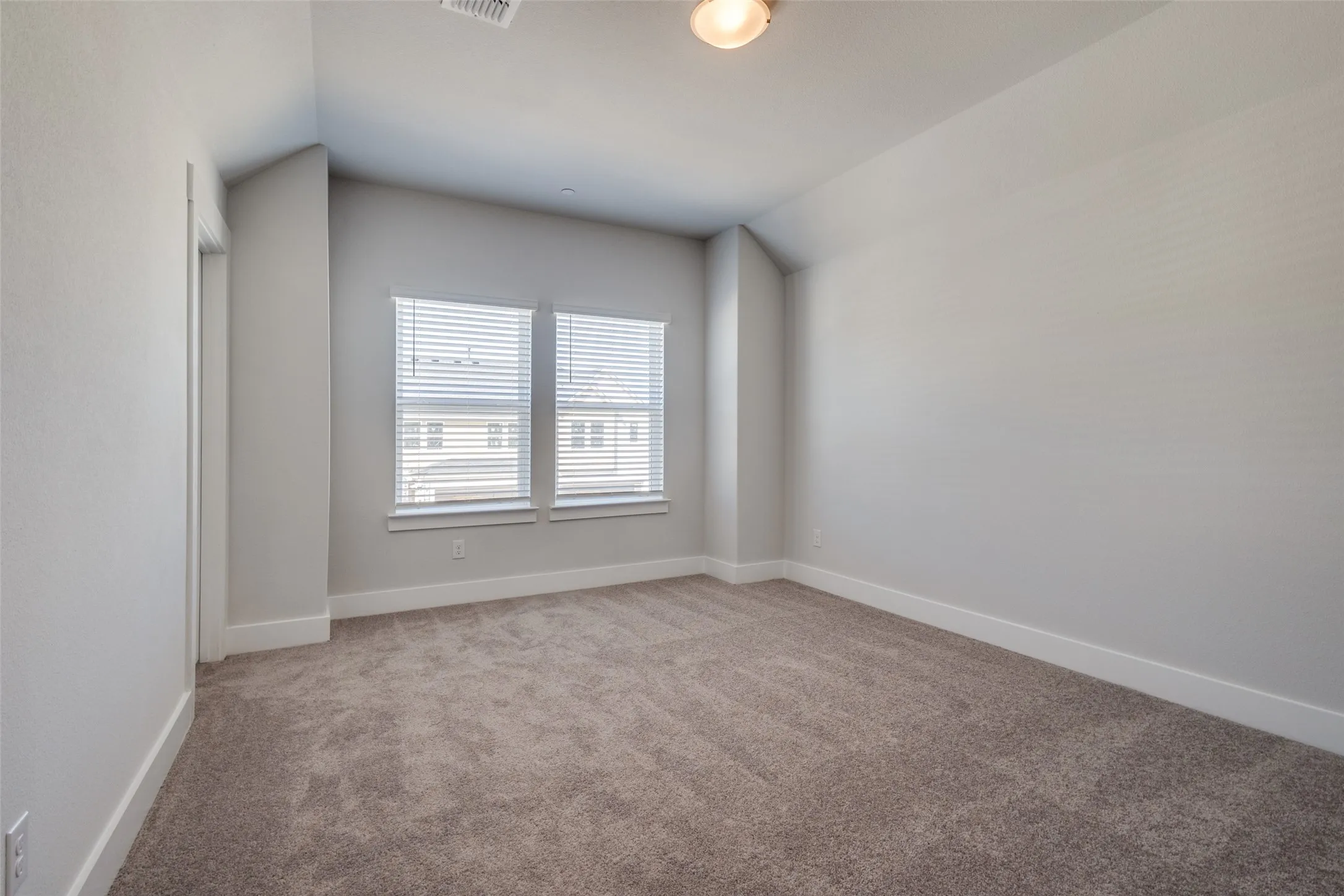 Carpeted spare room featuring vaulted ceiling