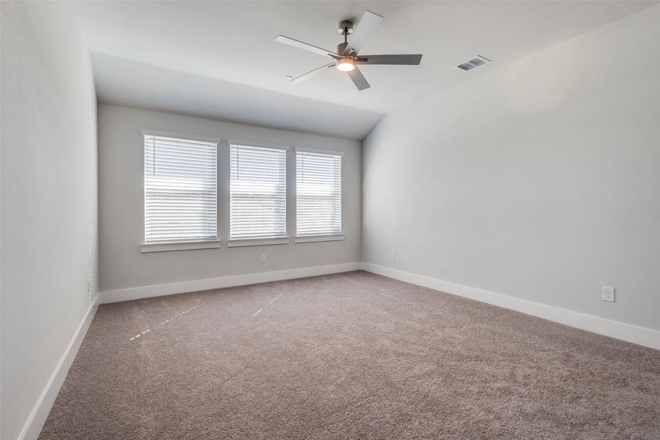 Carpeted empty room with ceiling fan and lofted ceiling
