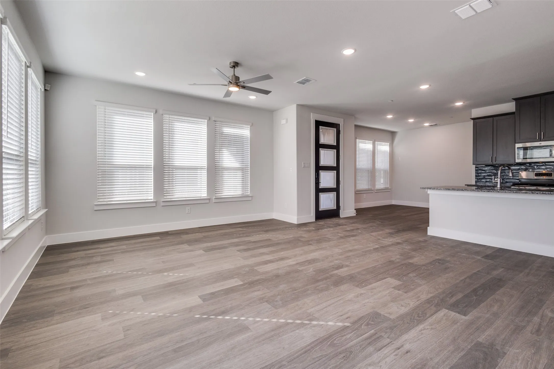 Unfurnished living room featuring ceiling fan, sink, a healthy amount of sunlight, and wood-type flooring