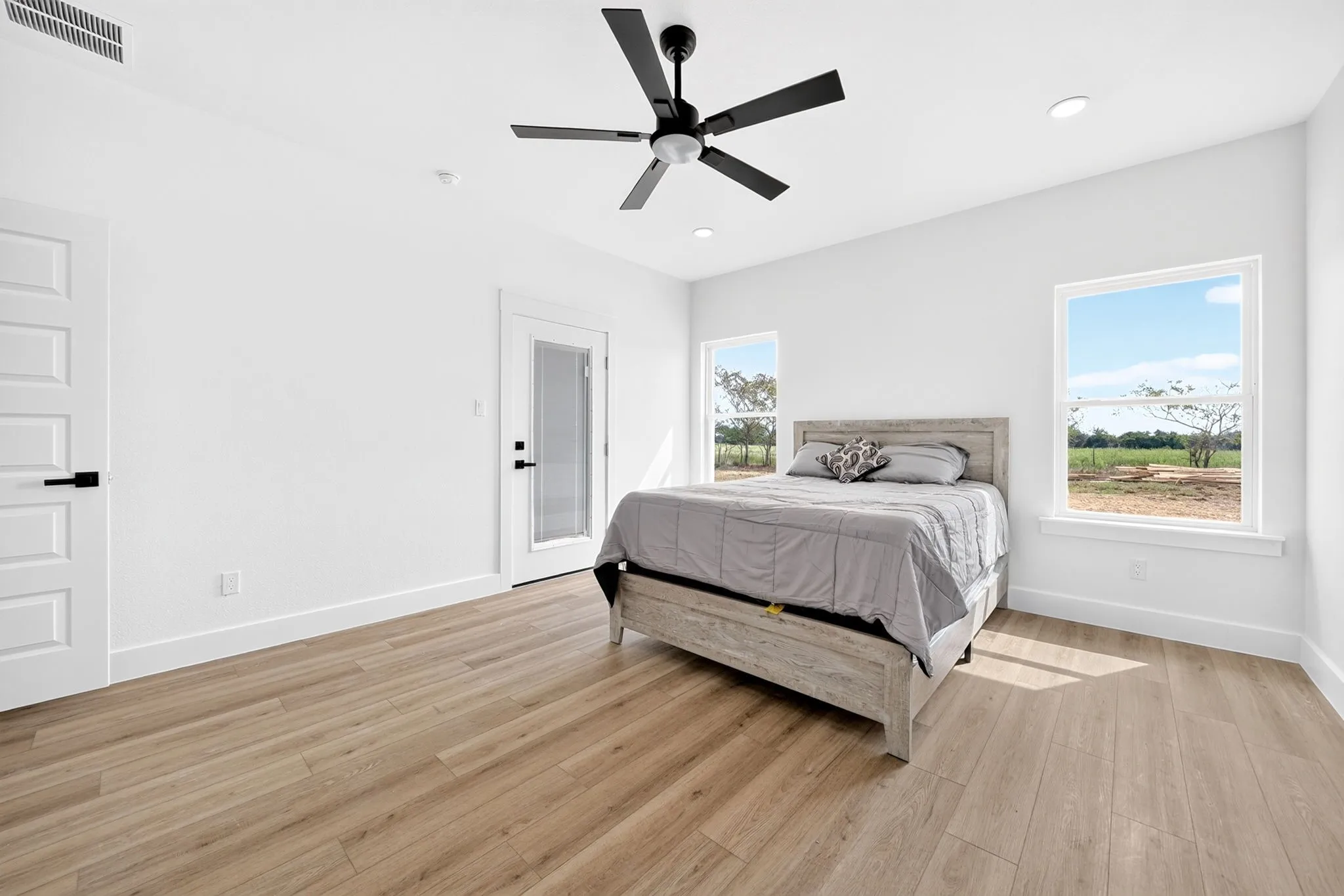 Spacious room with wood-finish flooring, recessed lighting, and a contemporary ceiling fan