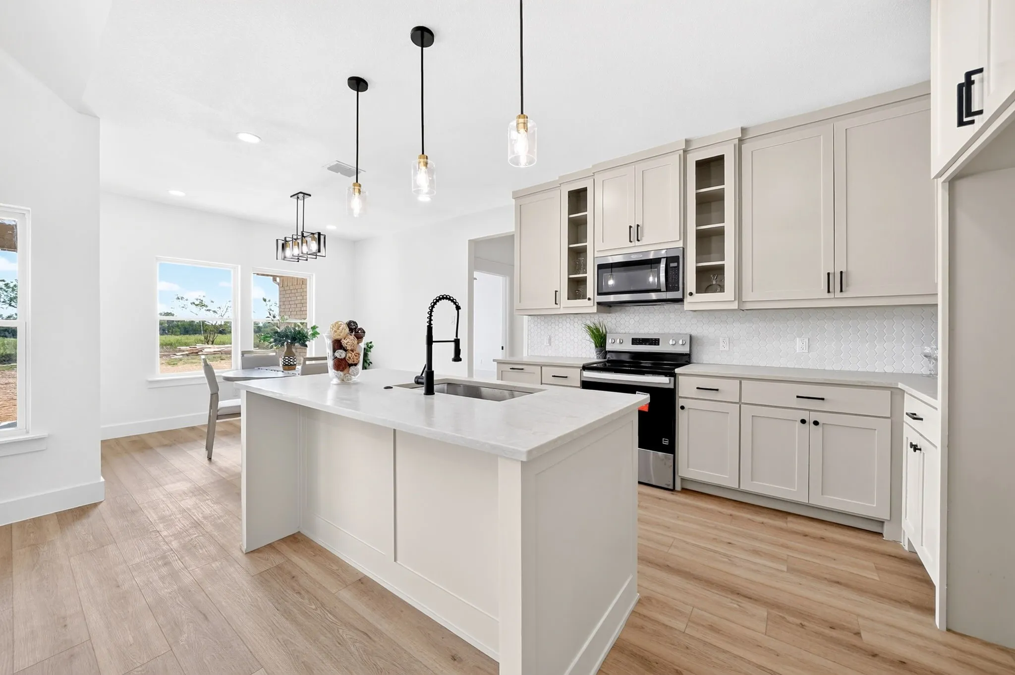 Kitchen featuring a central island with an undermount sink, light-toned cabinetry, stainless steel appliances, and wood-finish flooring