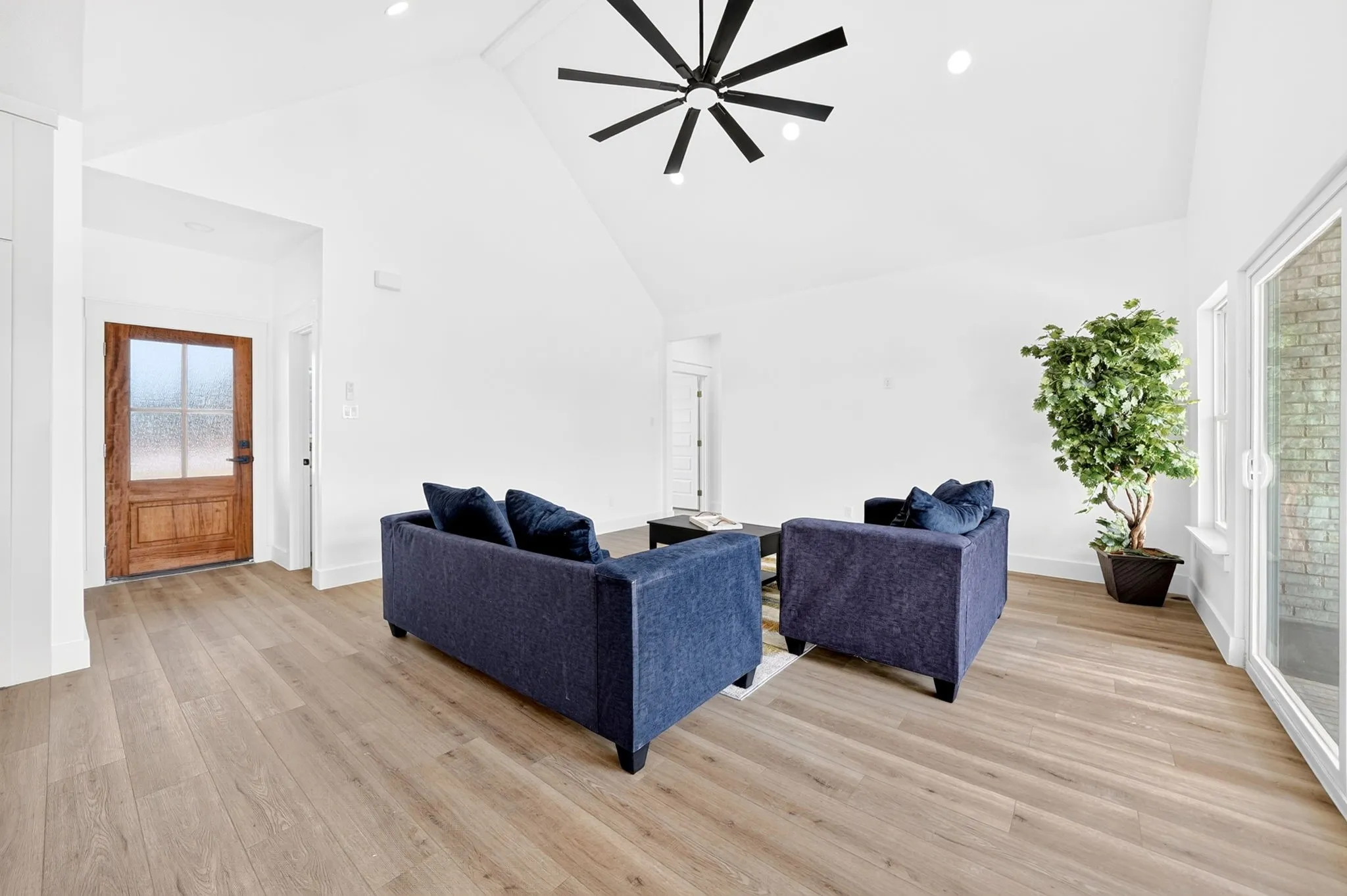 Vaulted ceiling with a black ceiling fan, recessed lighting, wood-finish flooring, and a glass-paneled wooden entry door