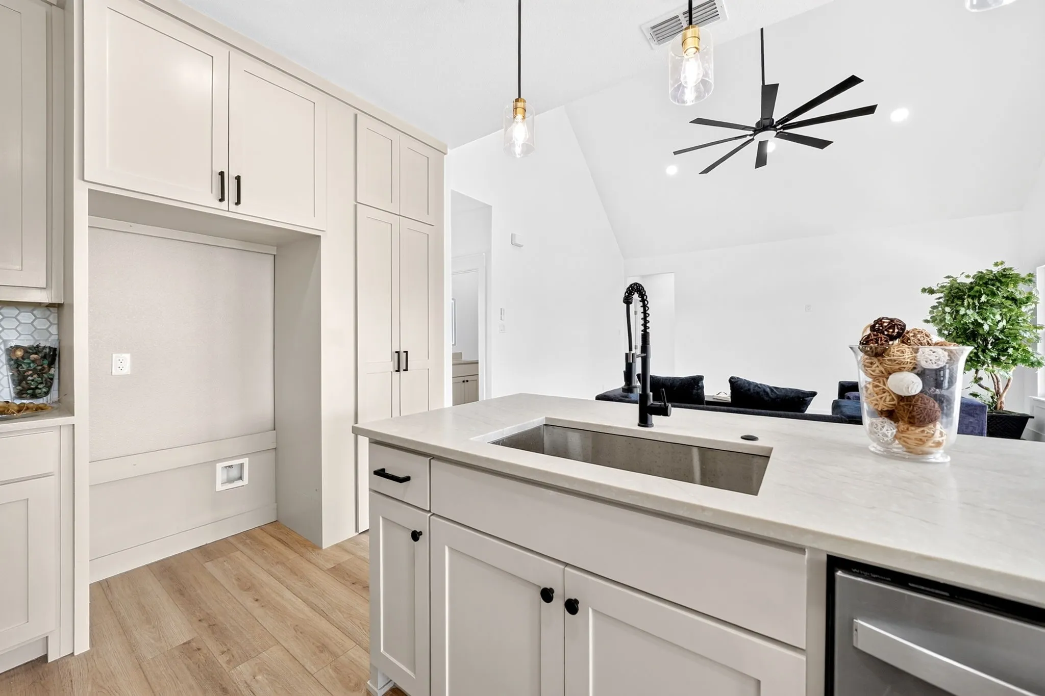 Kitchen featuring light-toned cabinetry, wood-finish flooring, a stainless steel sink with a matte black faucet, and pendant lighting