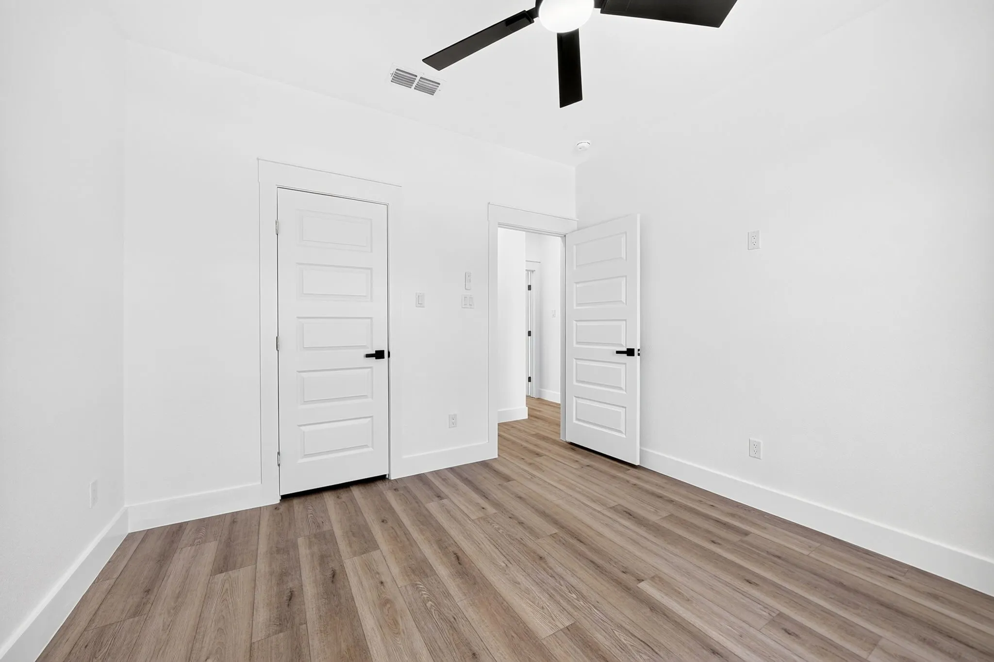 Recessed lighting, wood-finish flooring, contemporary ceiling fan, white paneled doors, and modern door hardware
