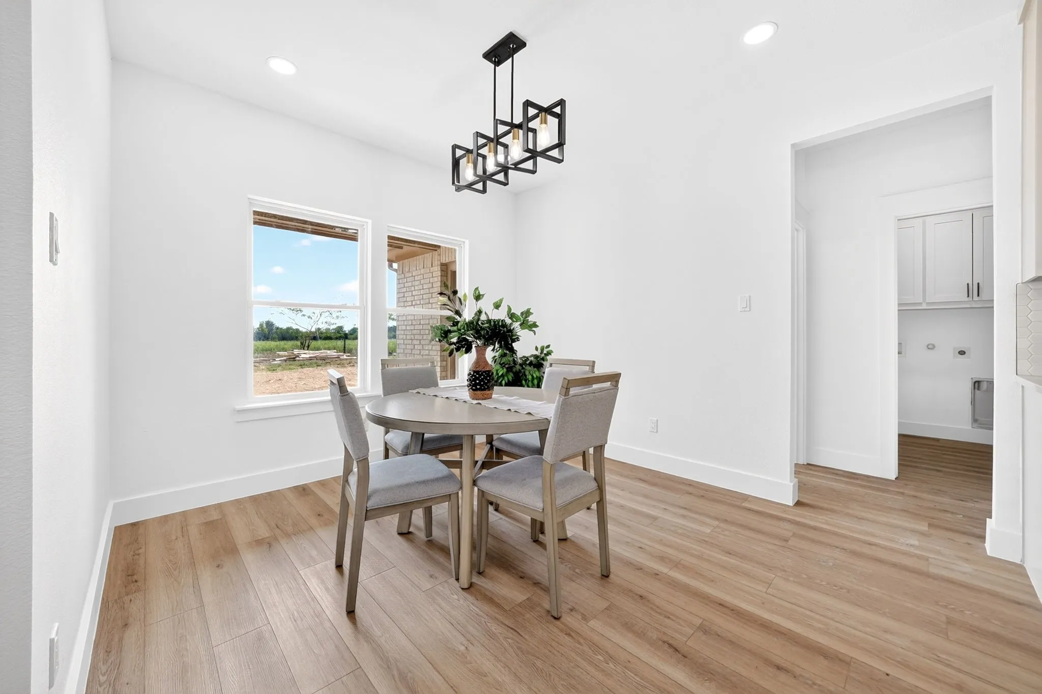 Wood-finish flooring, recessed ceiling lighting, and a modern black linear chandelier