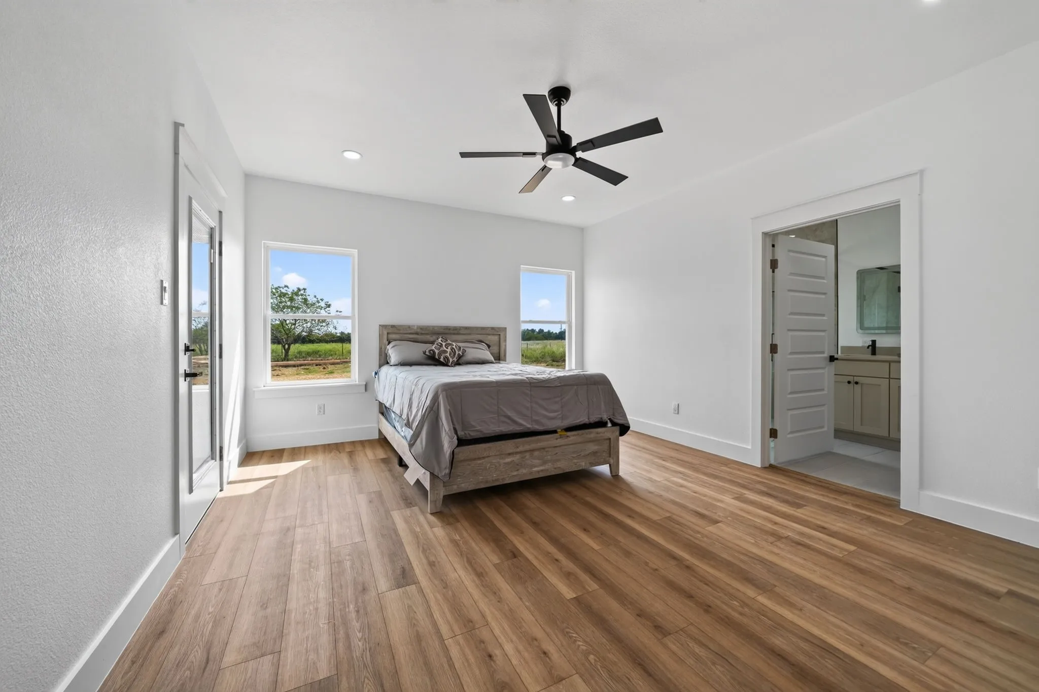 Wood-finish flooring throughout, bright white walls, and a contemporary ceiling fan