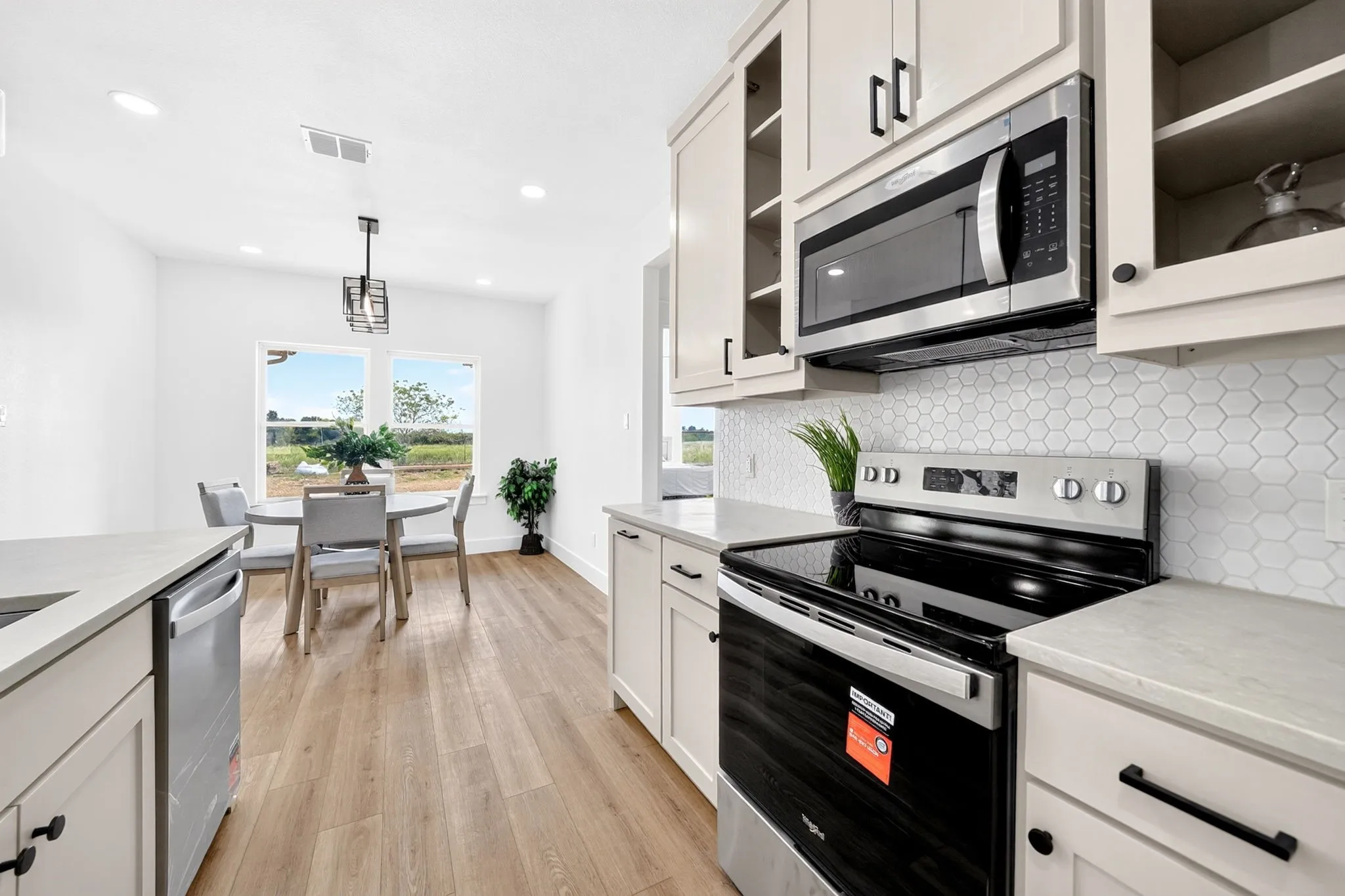 Kitchen featuring white cabinetry, light-toned countertops, a hexagonal tile backsplash, and wood-finish flooring