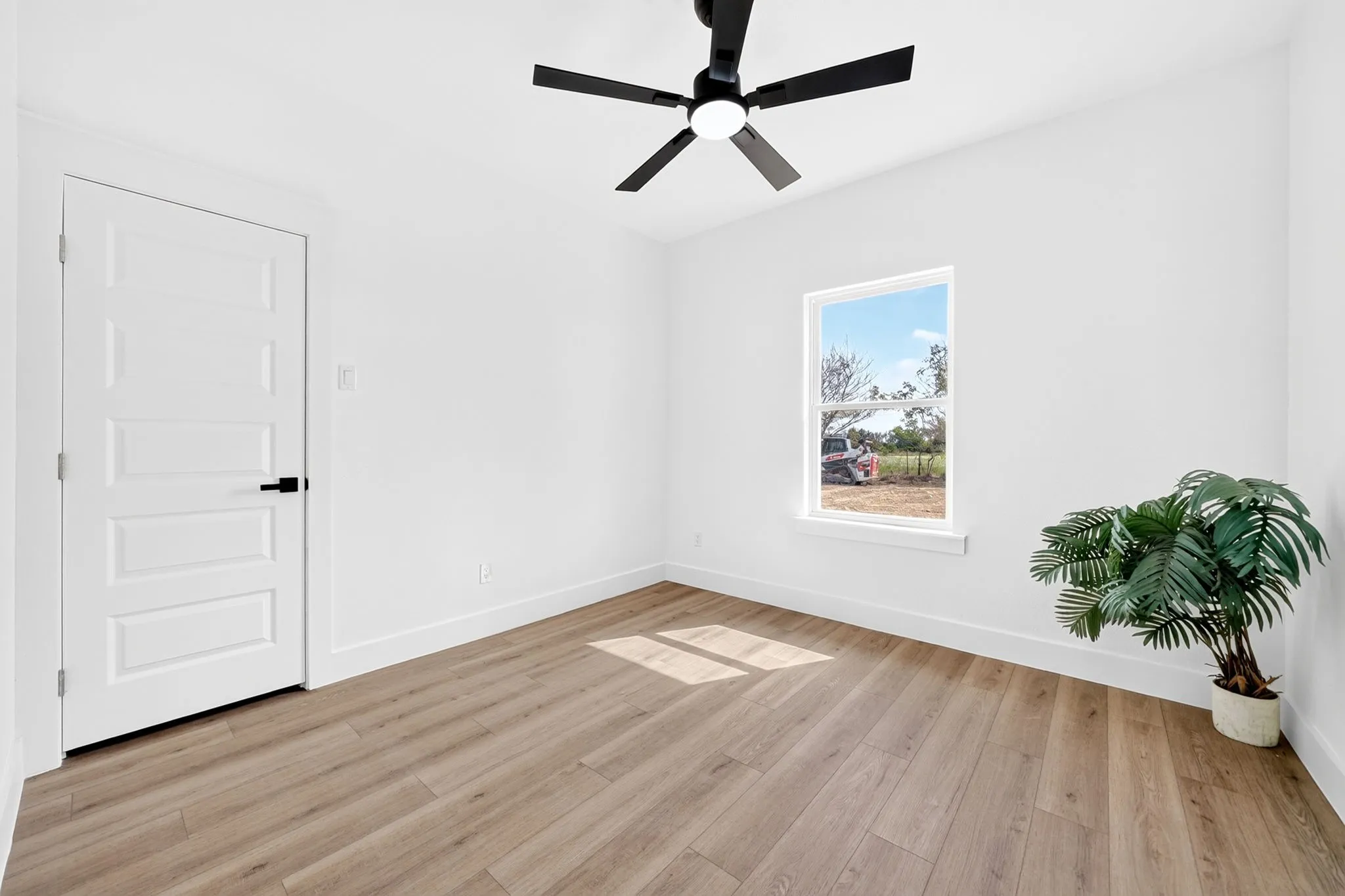 Wood-finish flooring, white walls, and a contemporary ceiling fan with integrated lighting