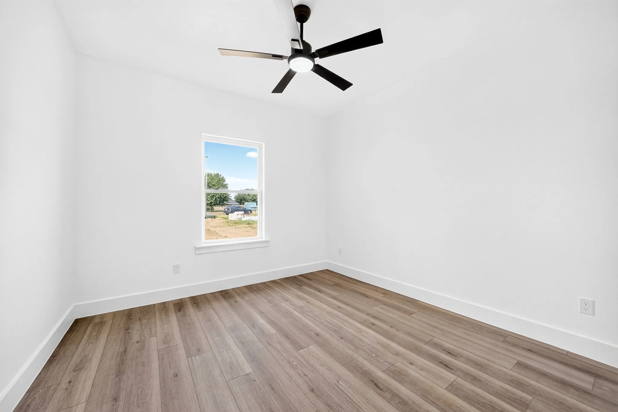 Wood-finish flooring, white walls, and a contemporary black ceiling fan with integrated lighting