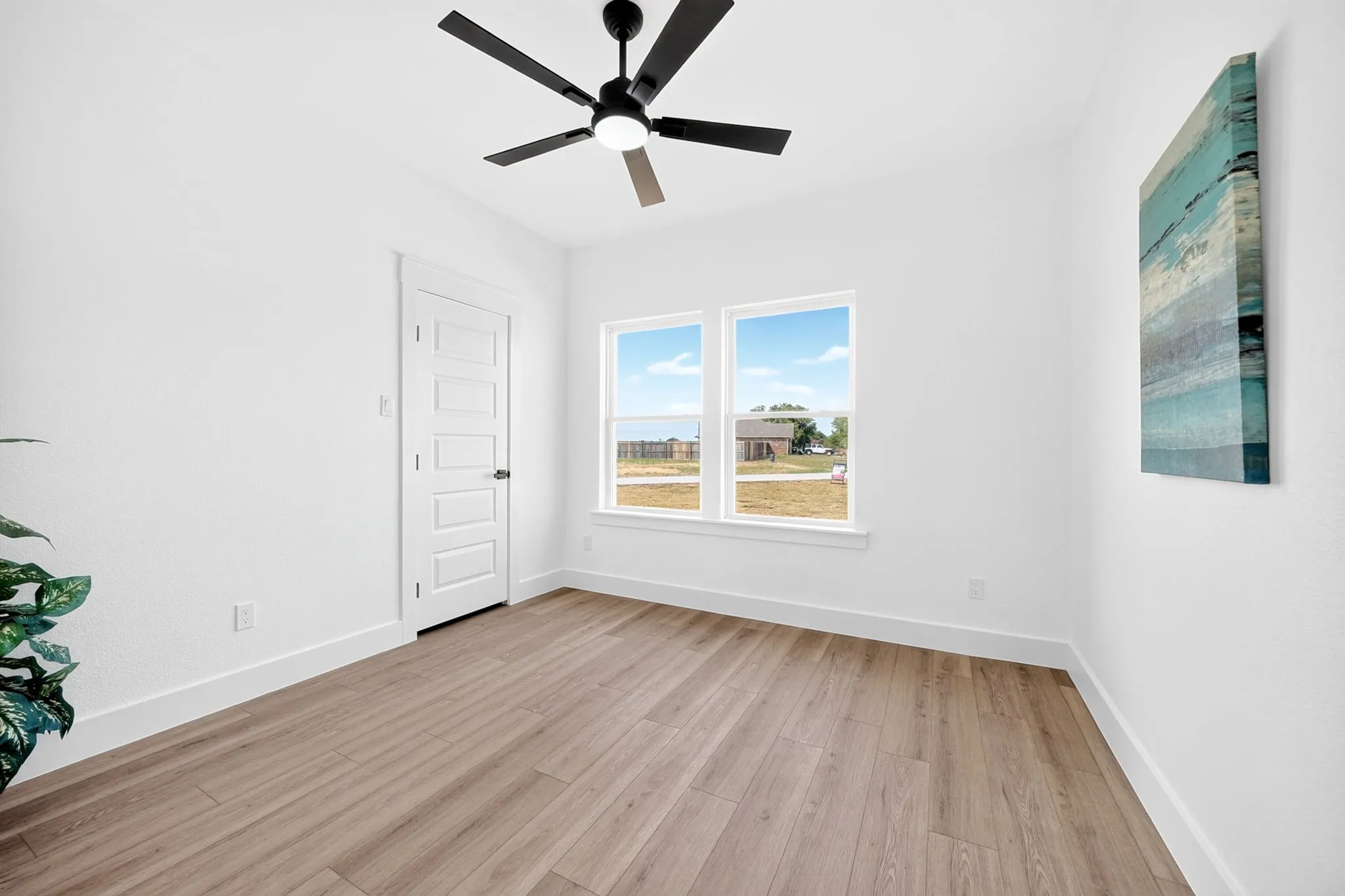 Wood-finish flooring, white walls, and a contemporary ceiling fan