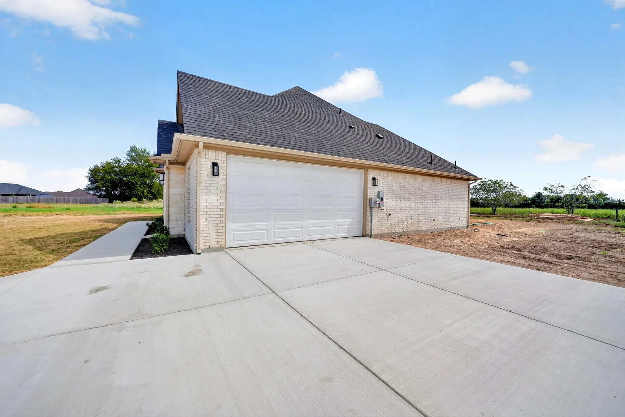 Brick exterior with dark shingle roof, attached garage, and paved driveway