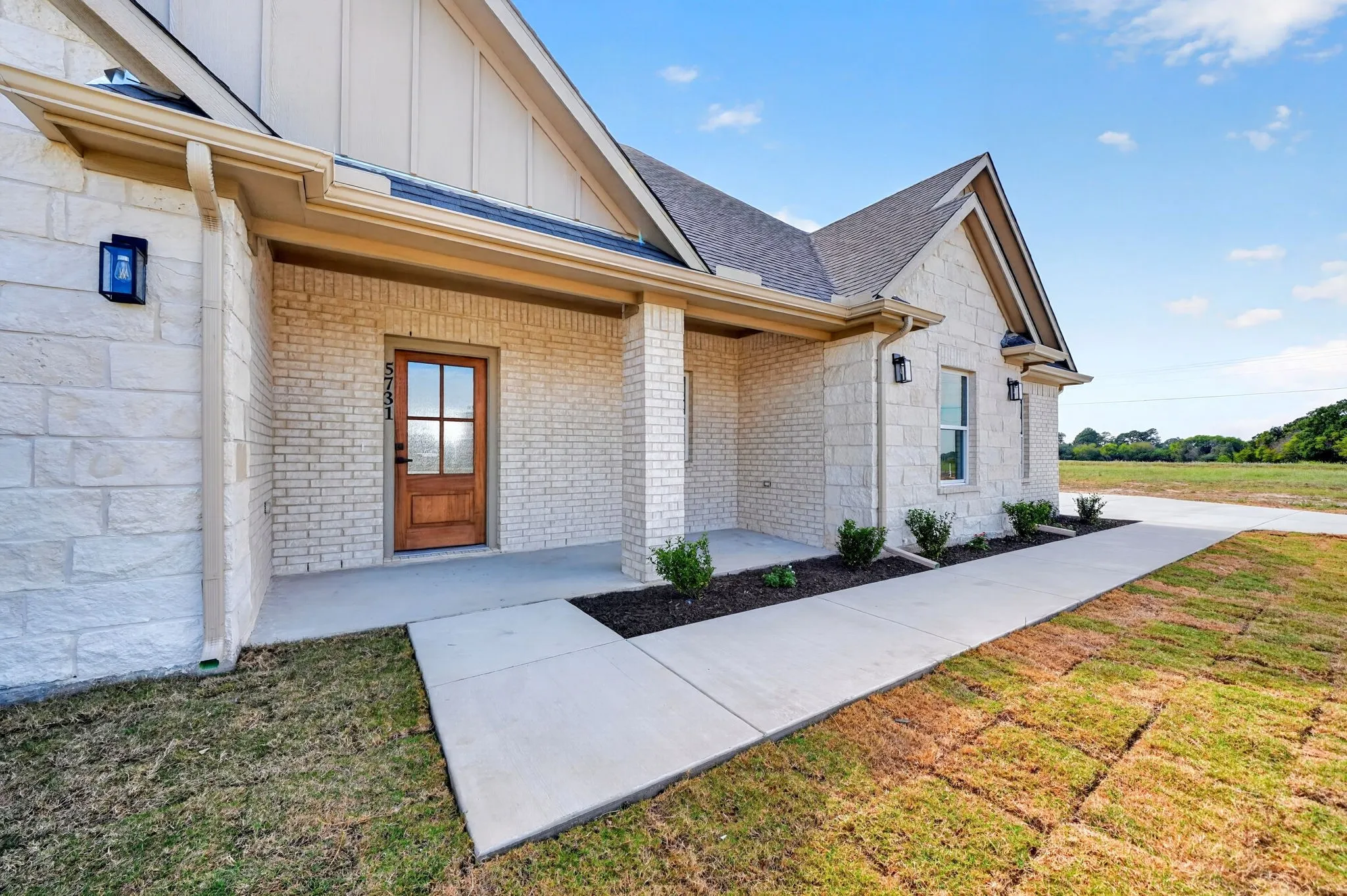 Stone and brick exterior with a covered entry and wood-finish front door