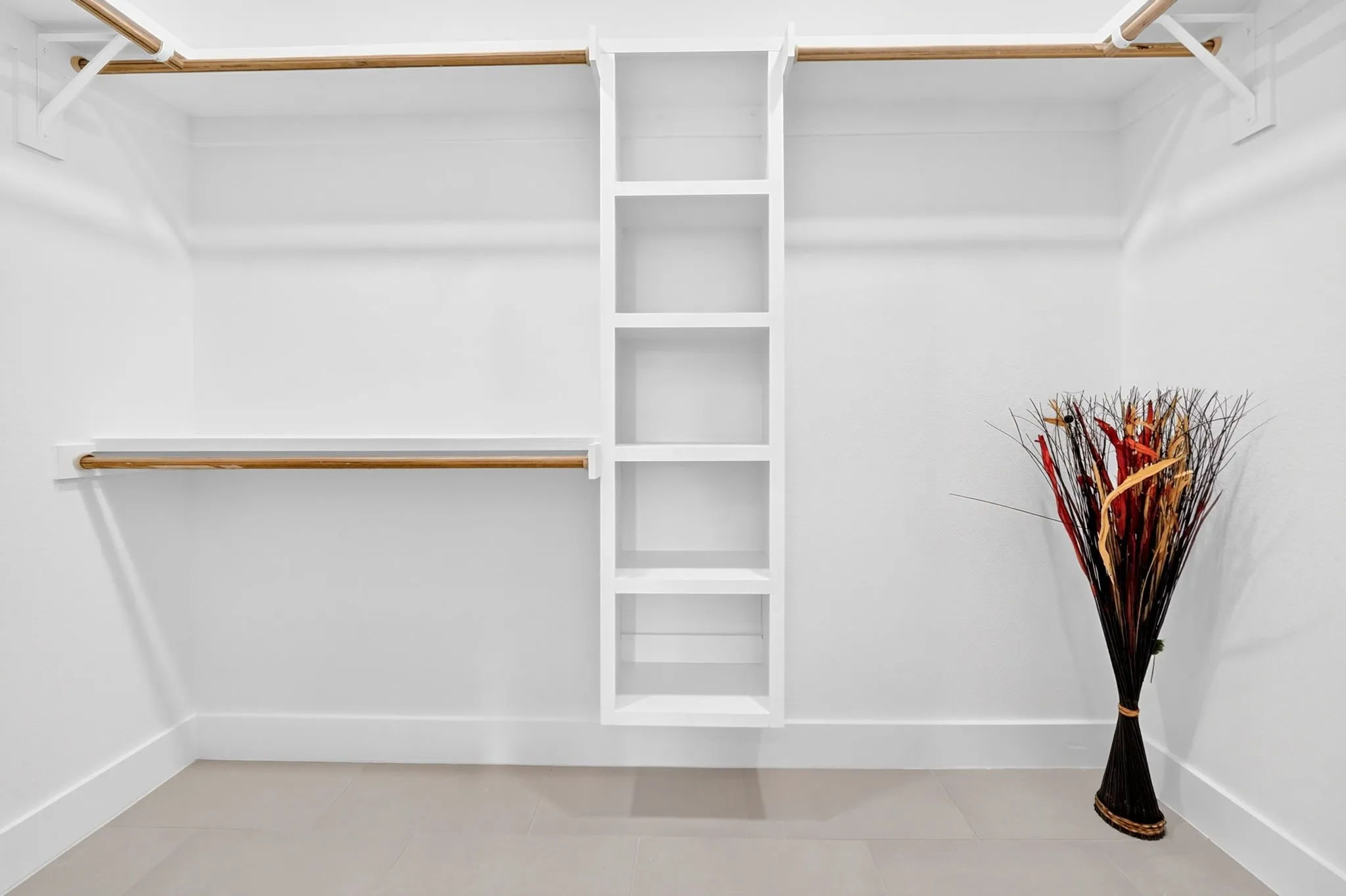 Built-in shelving unit, multiple hanging rods, and light-toned flooring