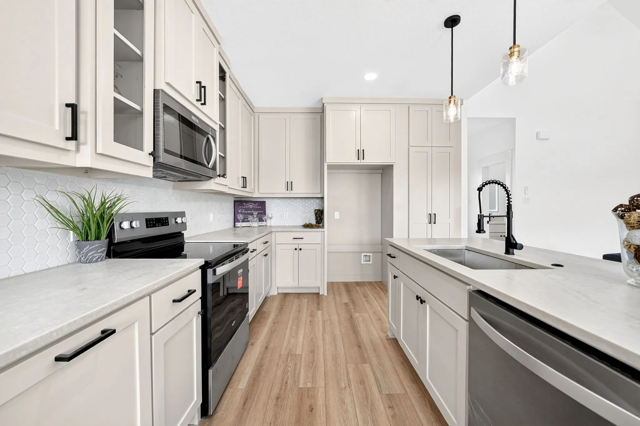 Kitchen featuring light cabinetry, a hexagonal tile backsplash, a stainless steel dishwasher, a black electric range, and wood-finish flooring