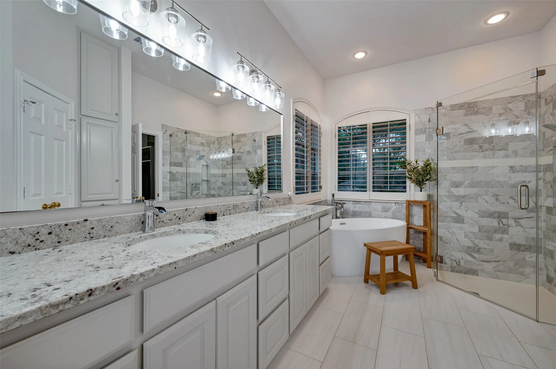 Ensuite primary bath recently completely remodeled with all new granite installed in Colonial White, matching the kitchen, dual vanities, a deep freestanding soaking tub, and an oversized walk-in shower