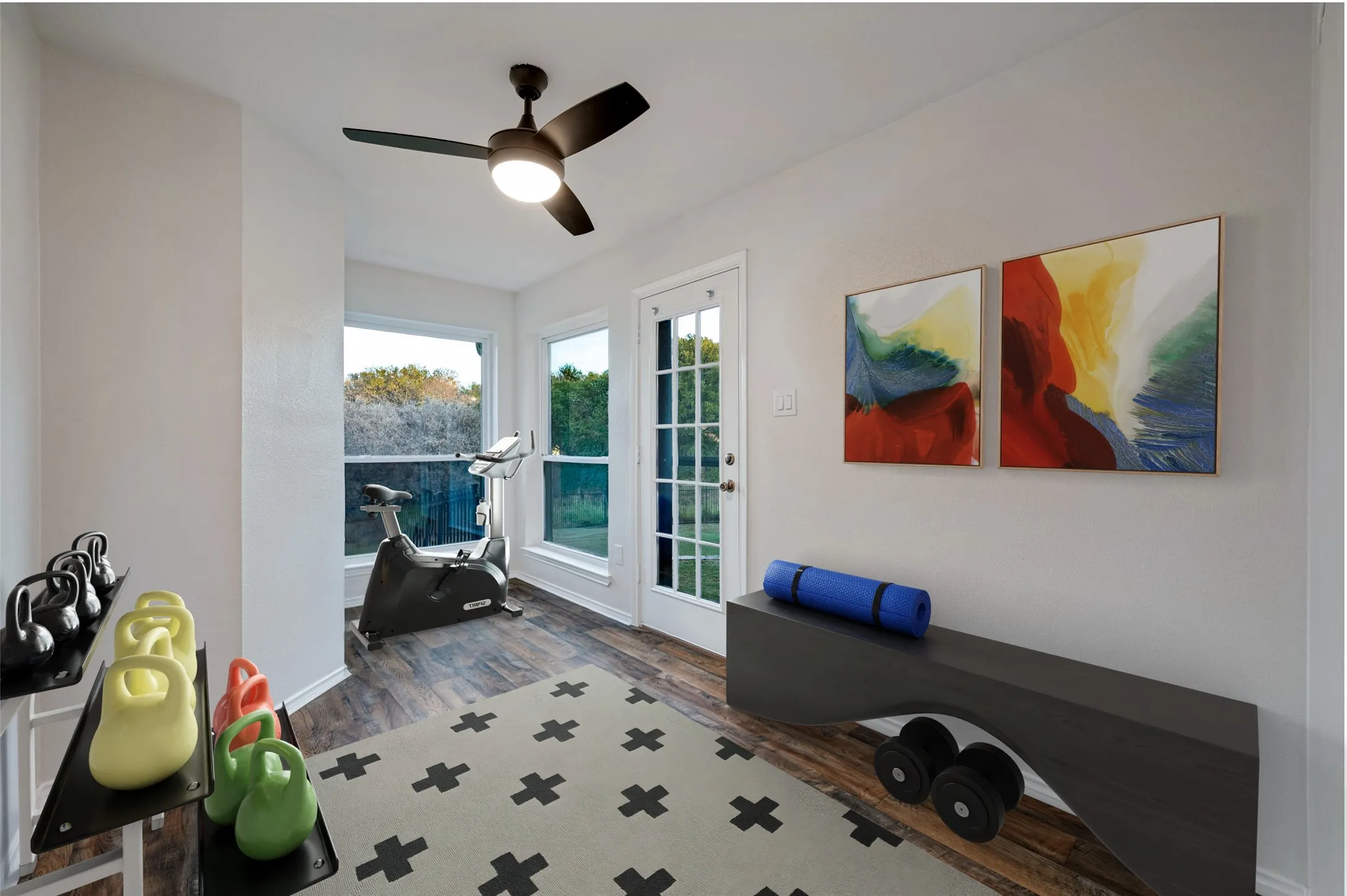 Flex space virtually staged as an exercise room. This room is beside the garage and features backyard views and an exterior door