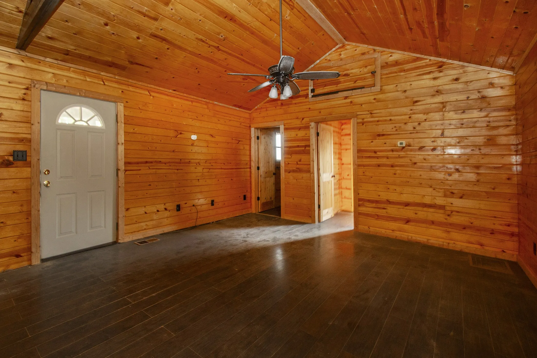 Wood-paneled walls and ceiling with a vaulted design, complemented by dark wood-finish flooring
