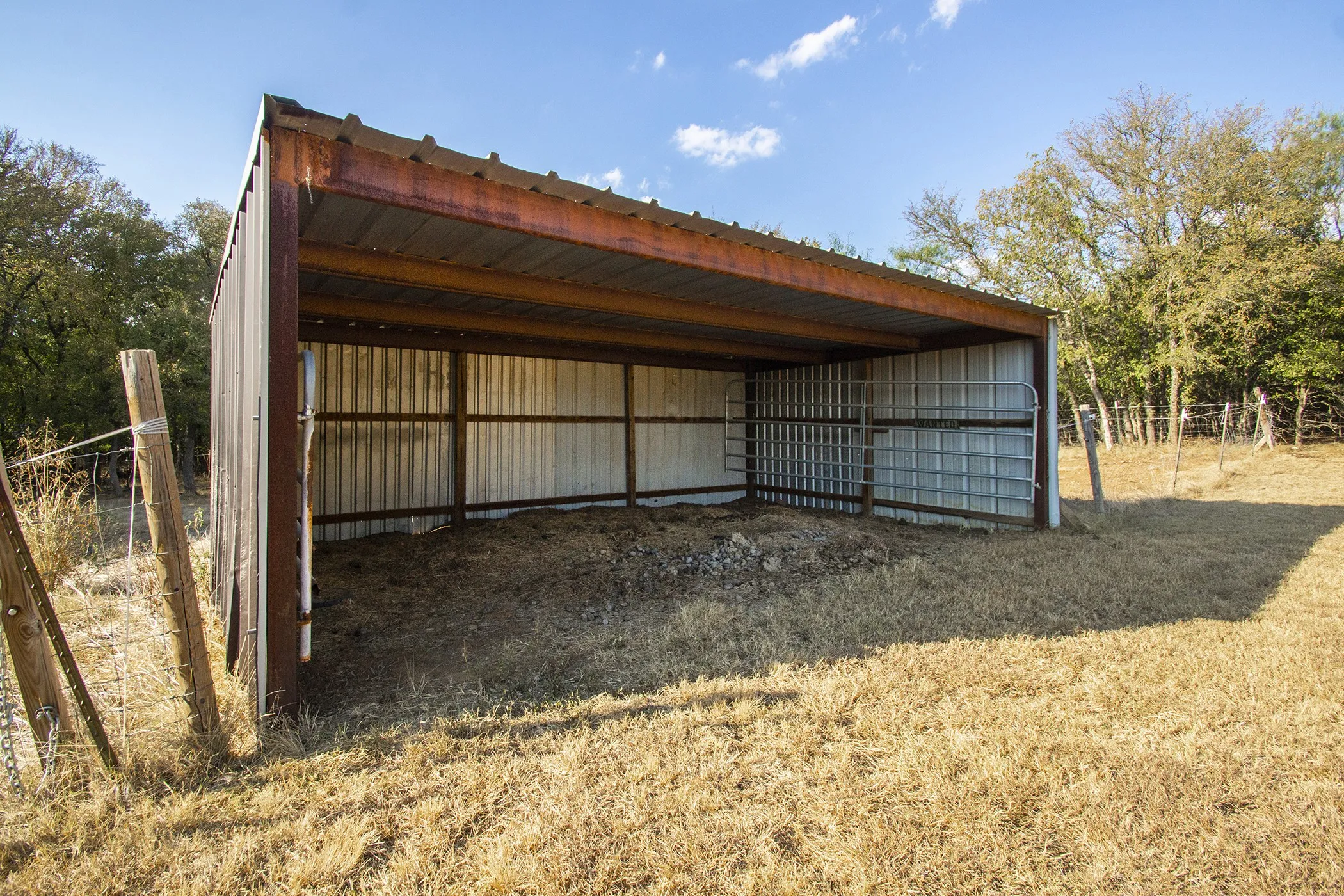 Metal-sided shelter with a corrugated roof and a fenced enclosure