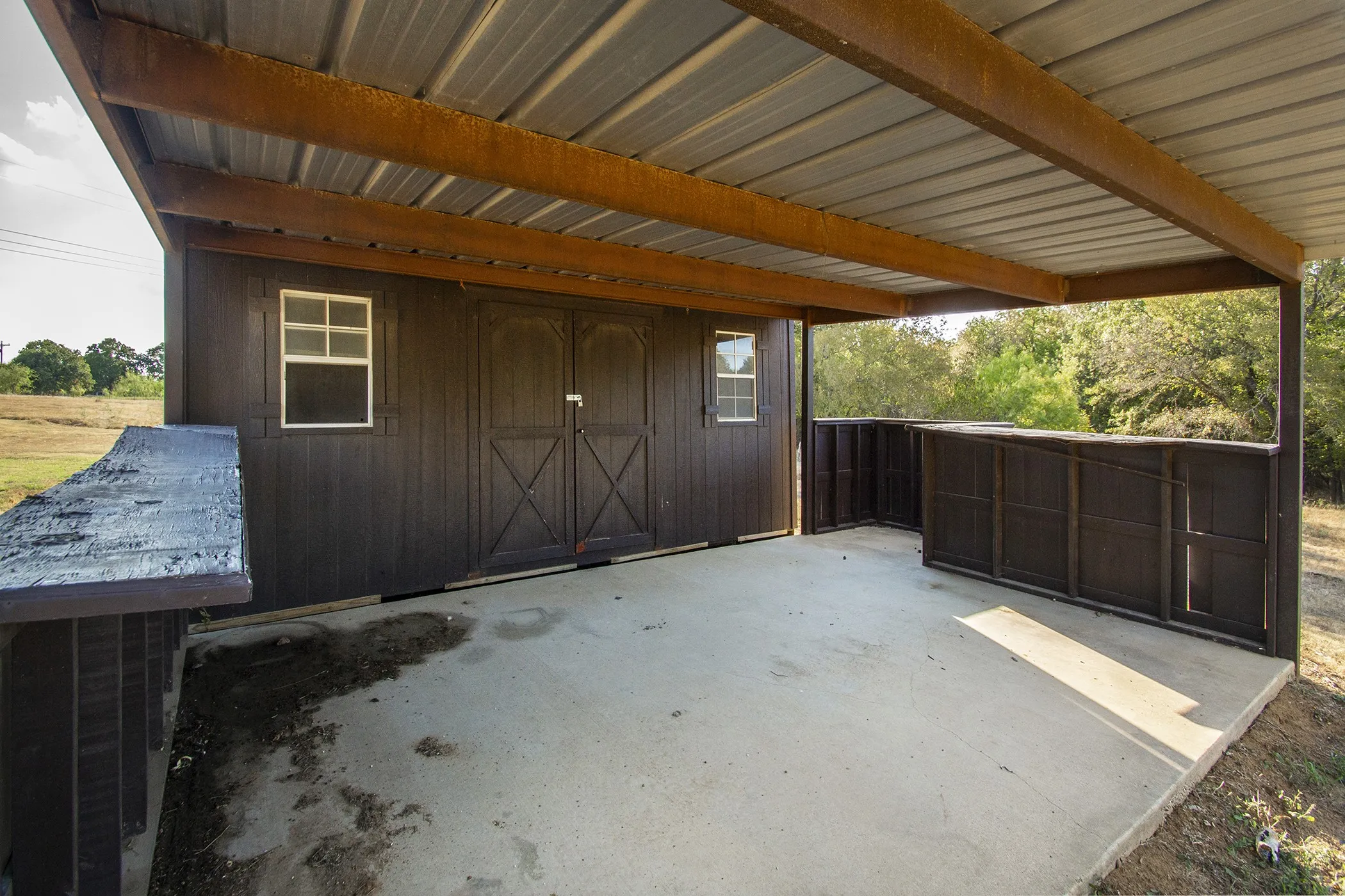 Covered concrete patio with a metal roof and exposed wood beams