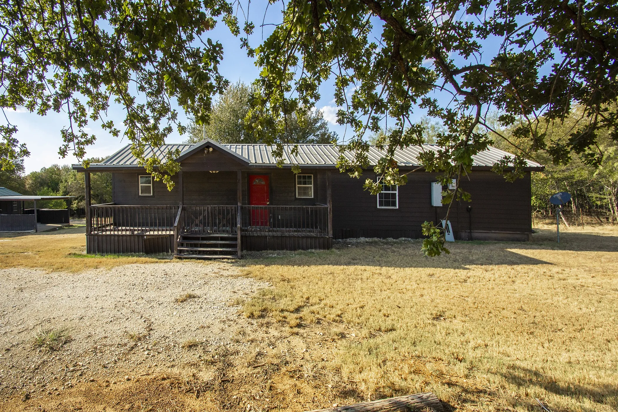 Wood-sided exterior with a covered porch, metal roof, and red entry door