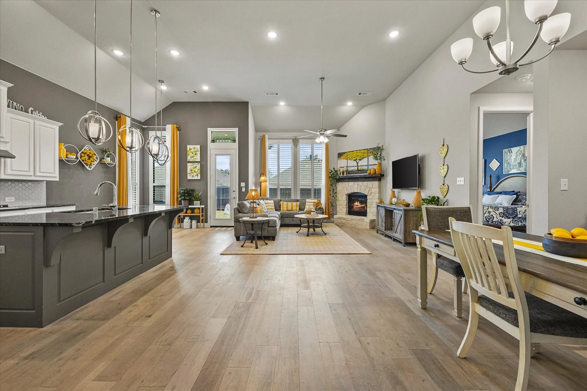 Spacious living area featuring high vaulted ceilings, light wood-finish flooring, and a stone-clad fireplace
